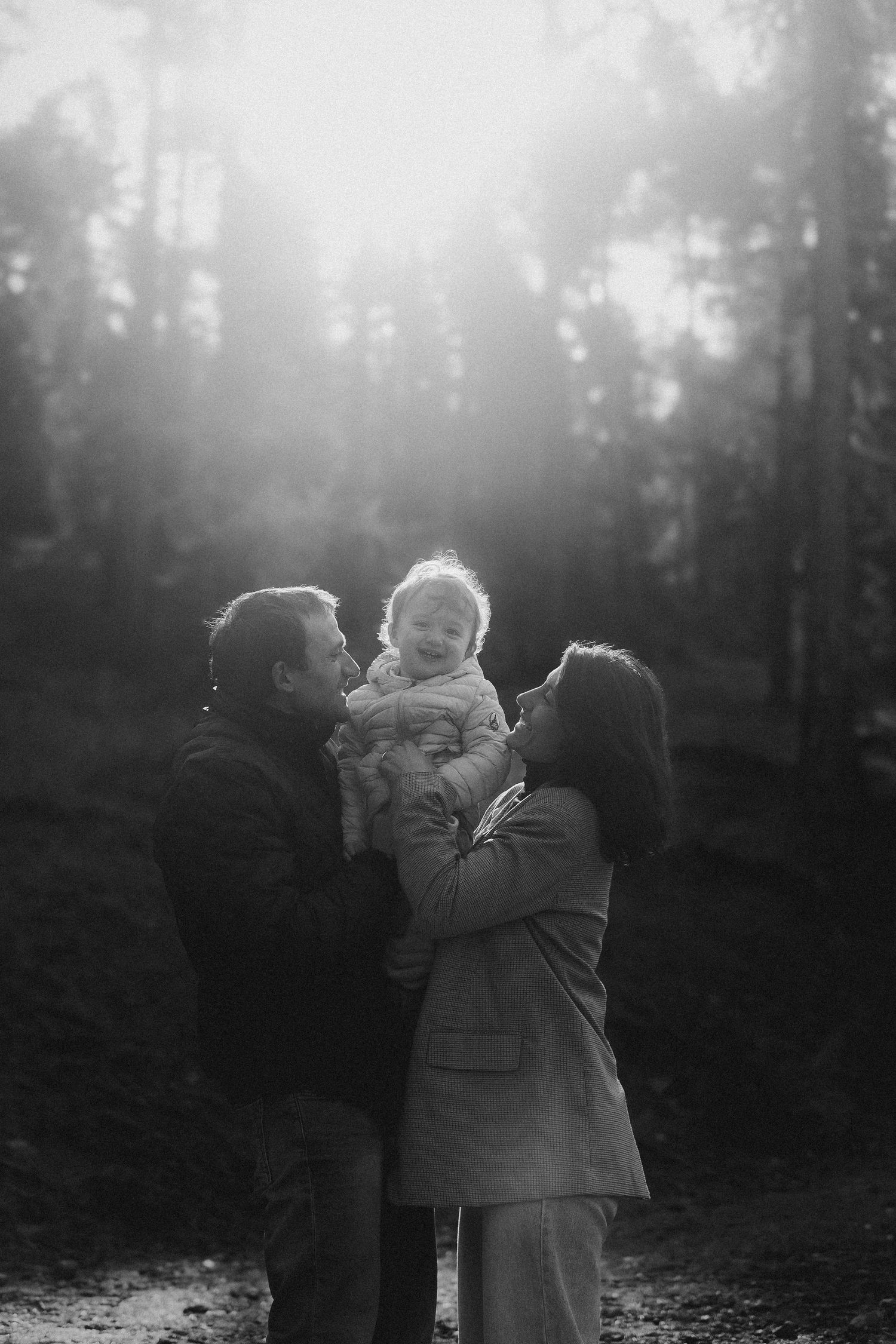 A black and white photo series showing two people embracing in a misty forest setting.