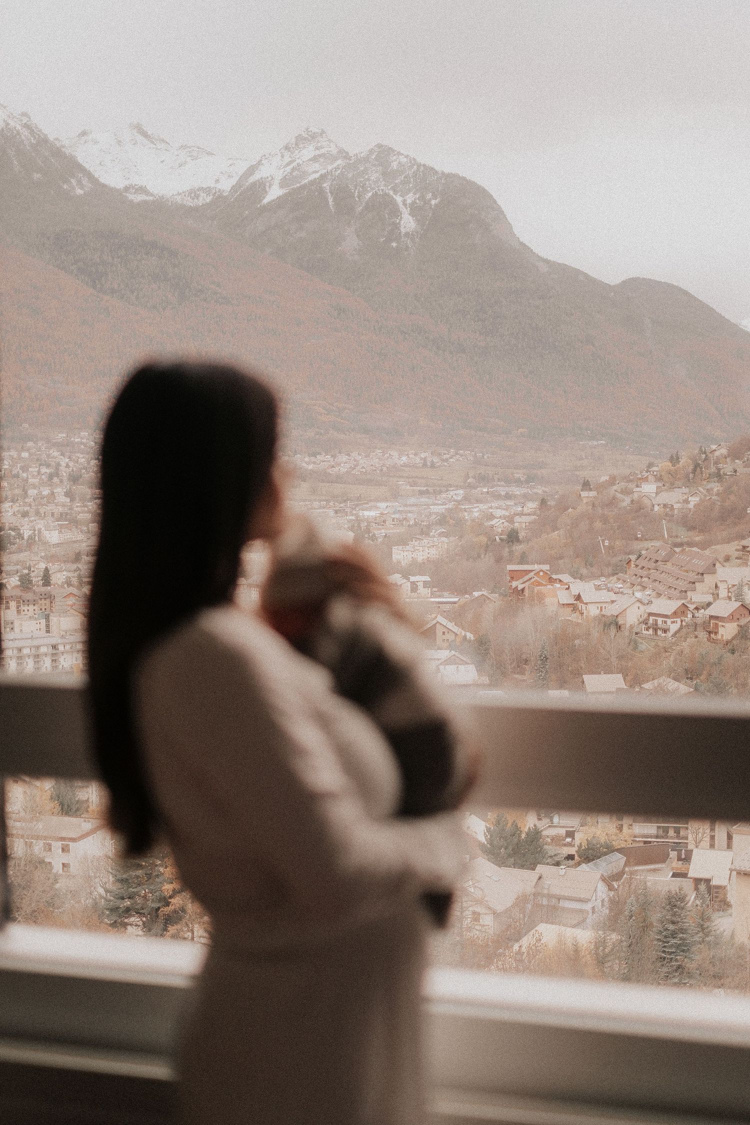 Silhouette of people looking out at a mountain landscape through large windows.