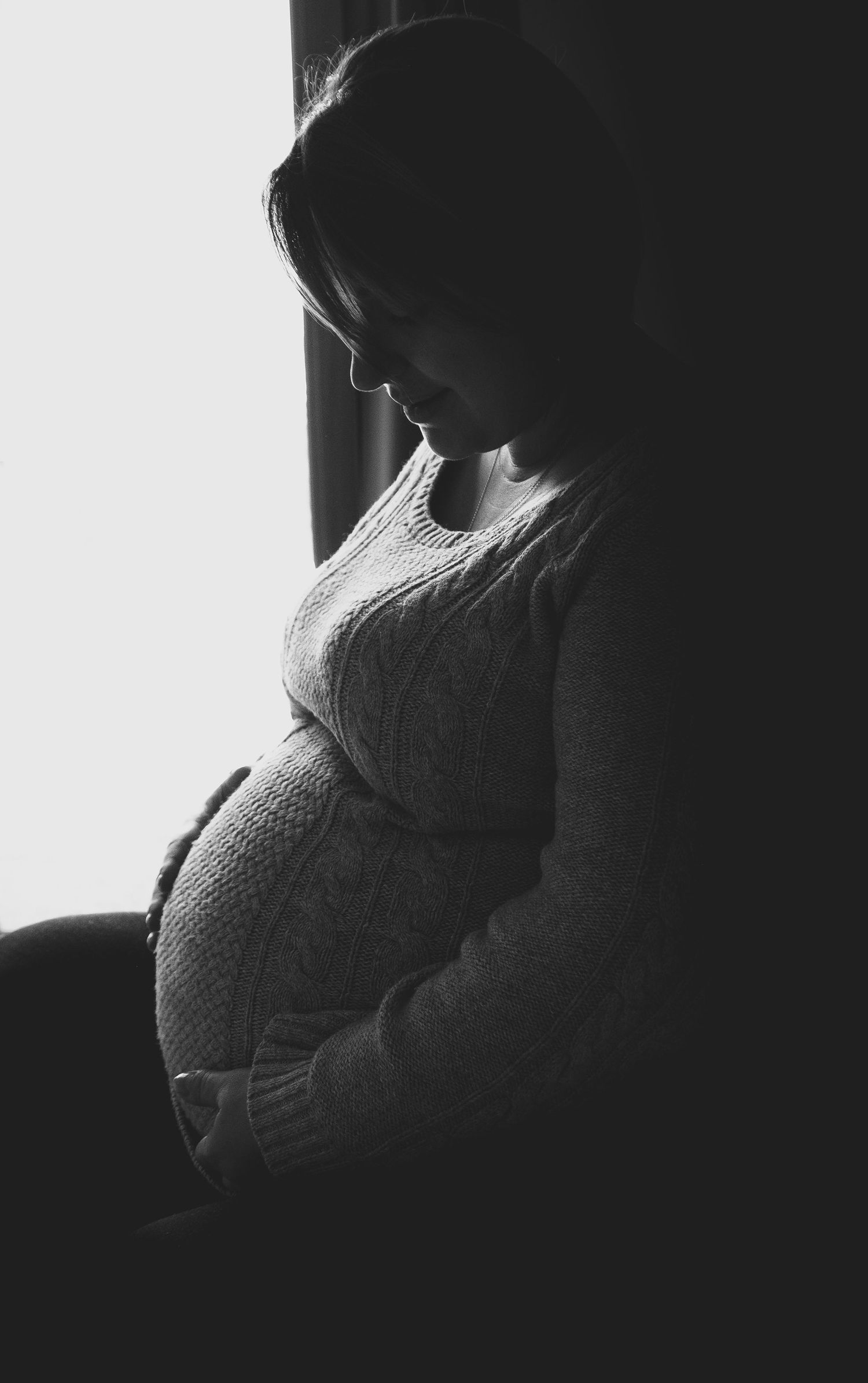 A black and white silhouette series showing the progression of a pregnant belly from early to late stages of pregnancy.