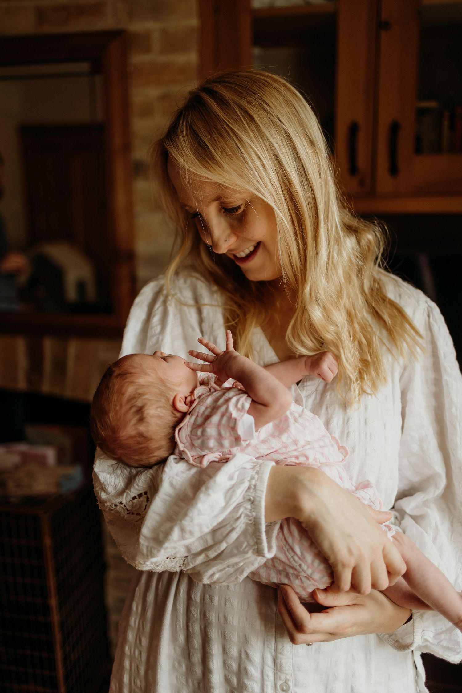 A gentle moment captured in soft indoor lighting with delicate white clothing.