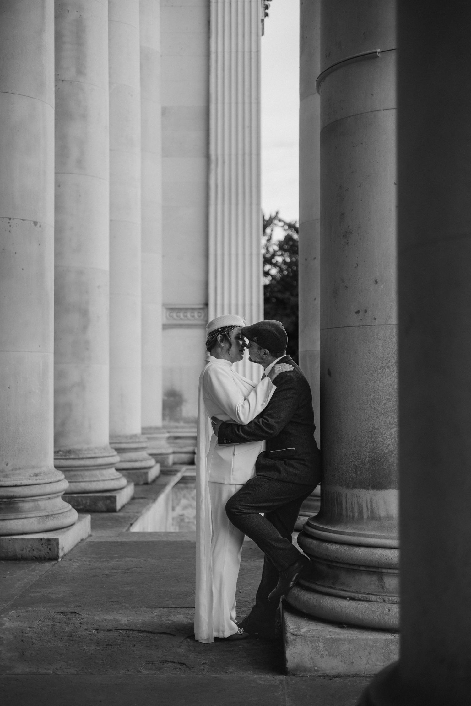 Artistic black and white wedding portraits captured between classic stone columns.