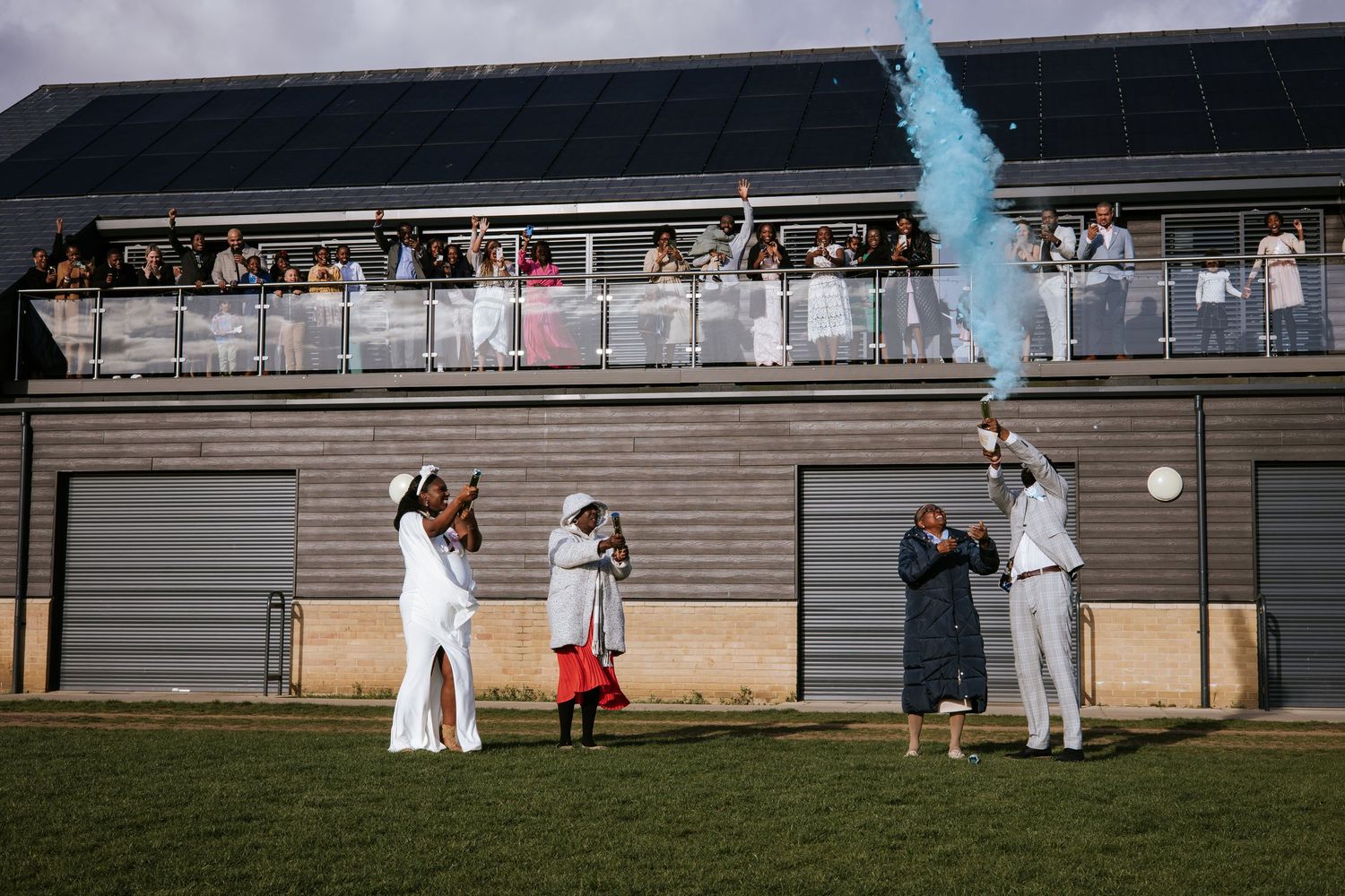 Outdoor celebration with blue smoke effects and guests in white attire.