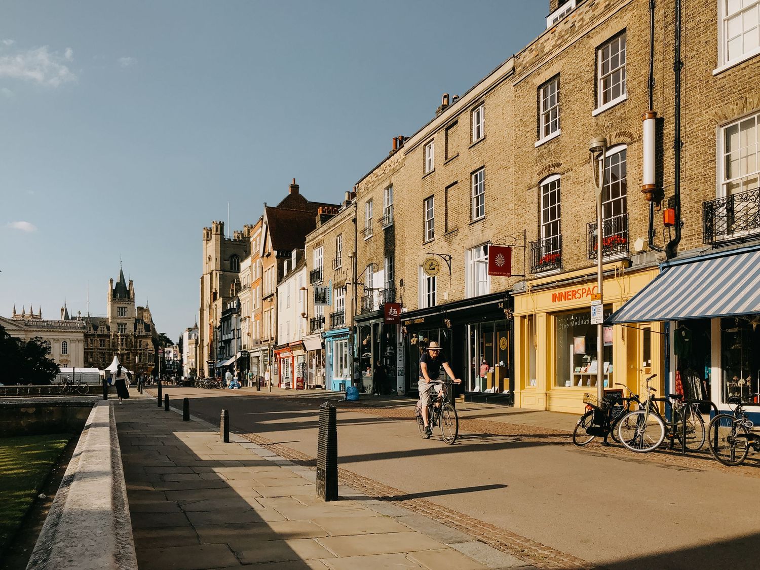 Historic stone buildings line a quiet cobblestone street in an English town center.