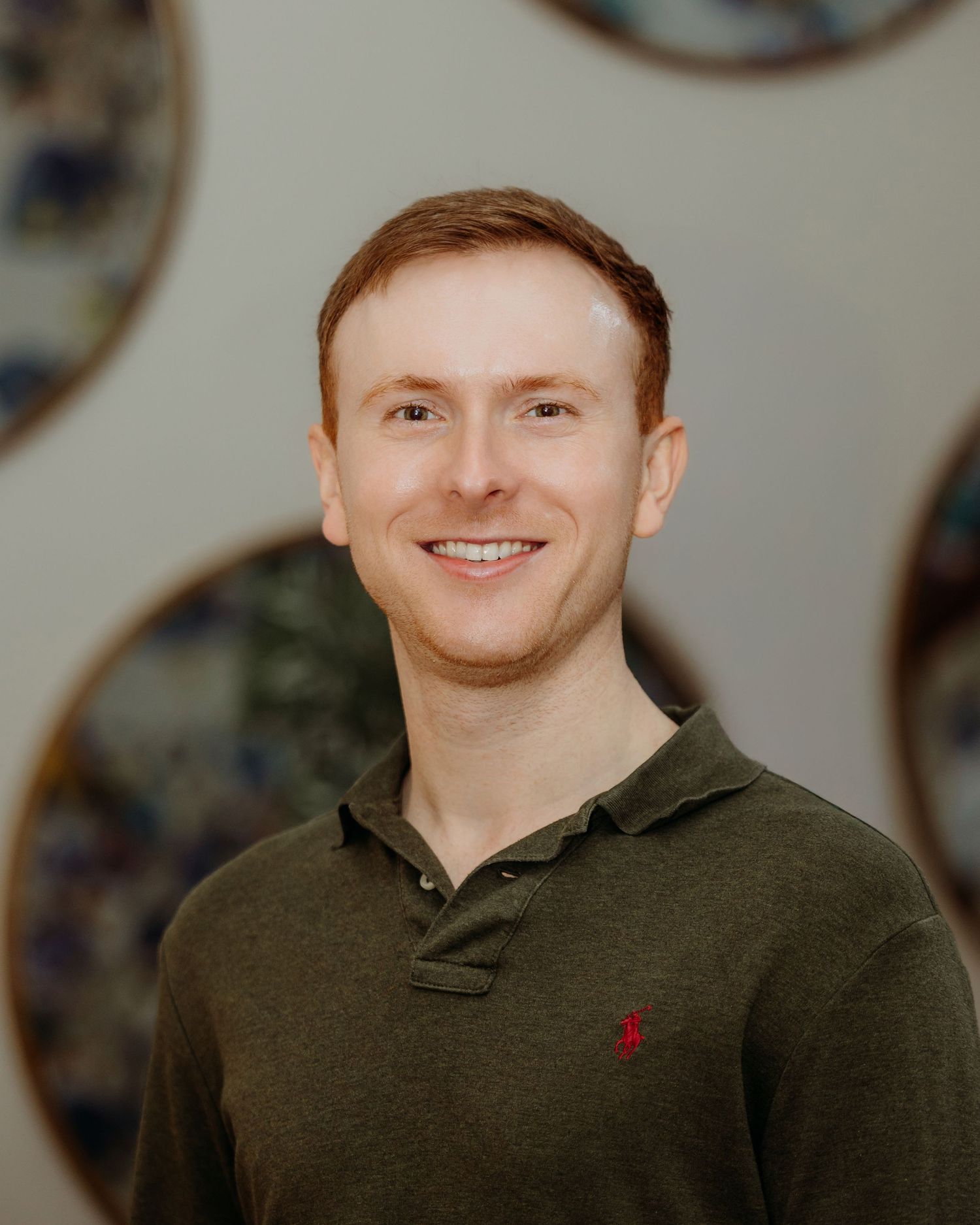 Professional headshot of someone in an olive green polo shirt against a neutral background.