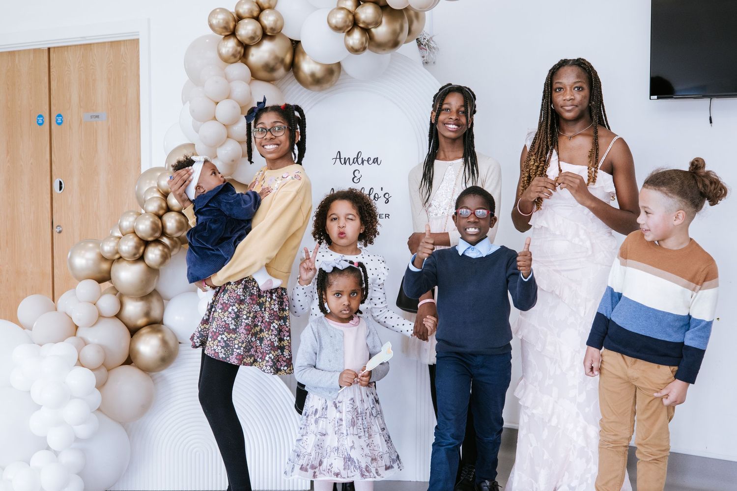 Festive celebration with balloon decorations and guests in white and floral outfits.