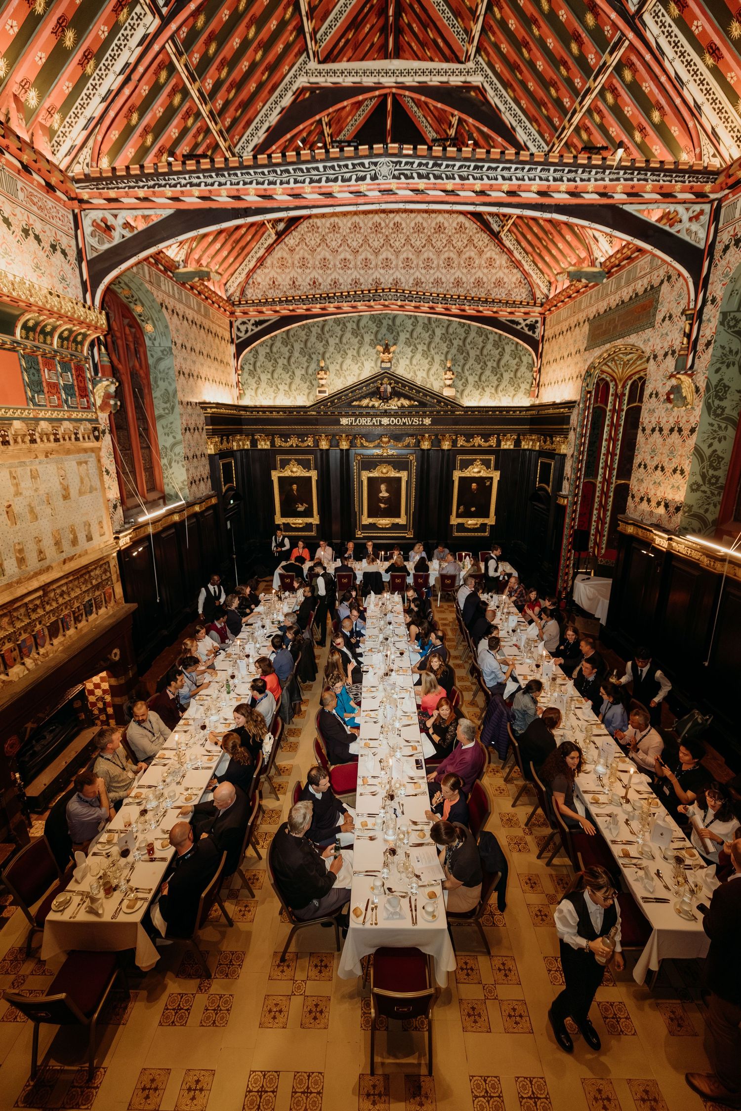 Grand dining hall with ornate painted ceiling and long tables set for a formal banquet.