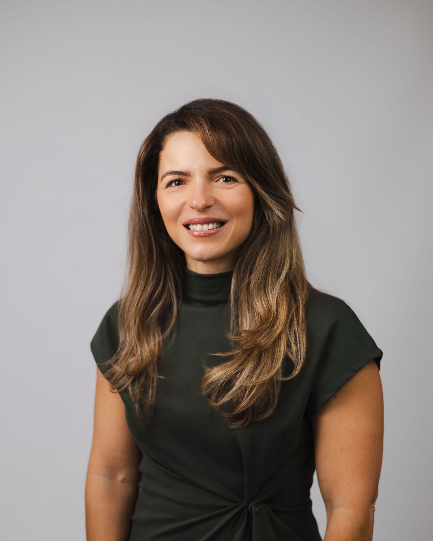 Professional headshots showing different expressions in a dark turtleneck against grey background.