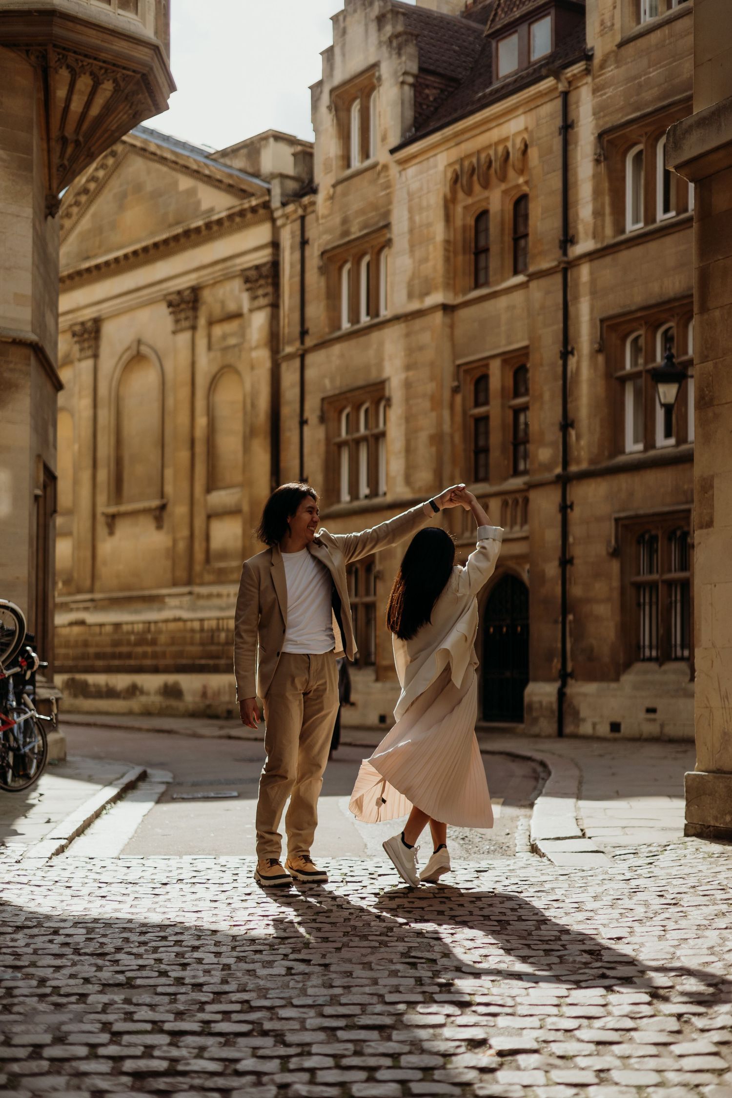 A couple dances and twirls on historic cobblestone streets surrounded by stone buildings.