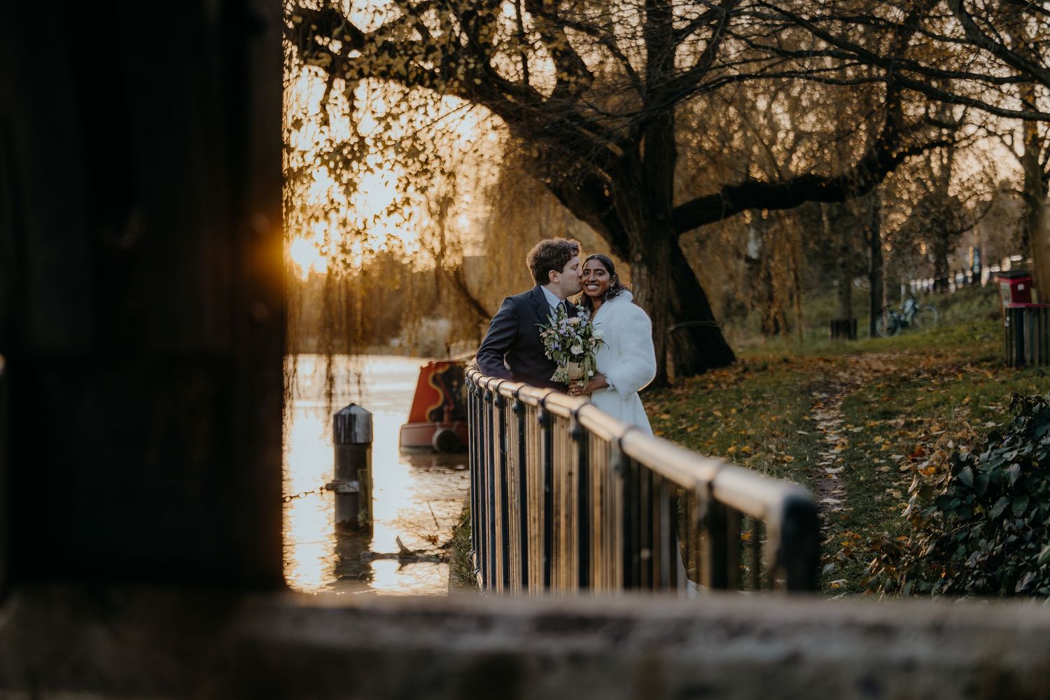 A romantic walkway framed by arches and trees with a couple in the distance.