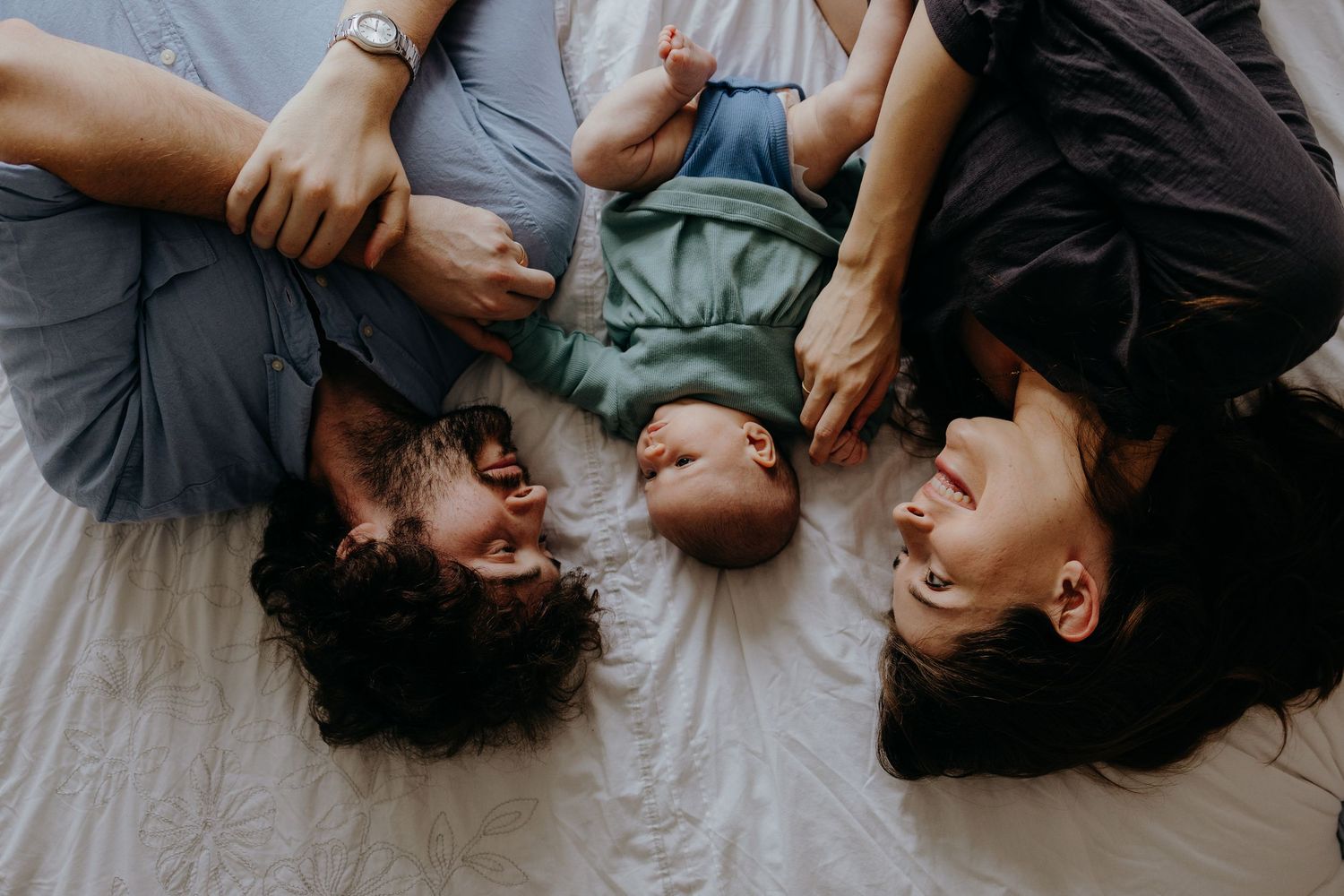 Three people lying on a bed together sharing a joyful moment of laughter and connection.