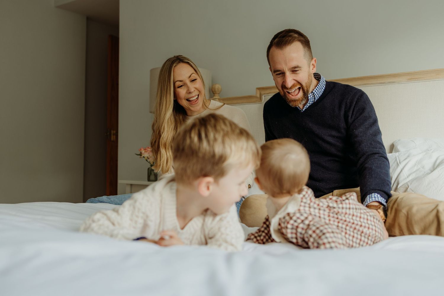 Family enjoying a playful moment together on a cozy bed with white linens.