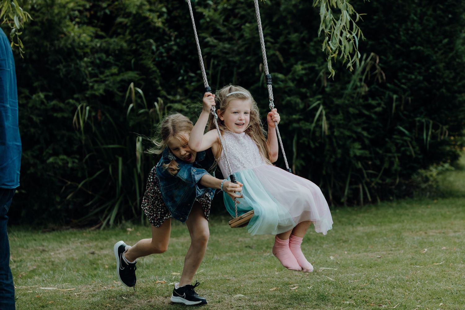Children playing on swings in a lush garden setting.
