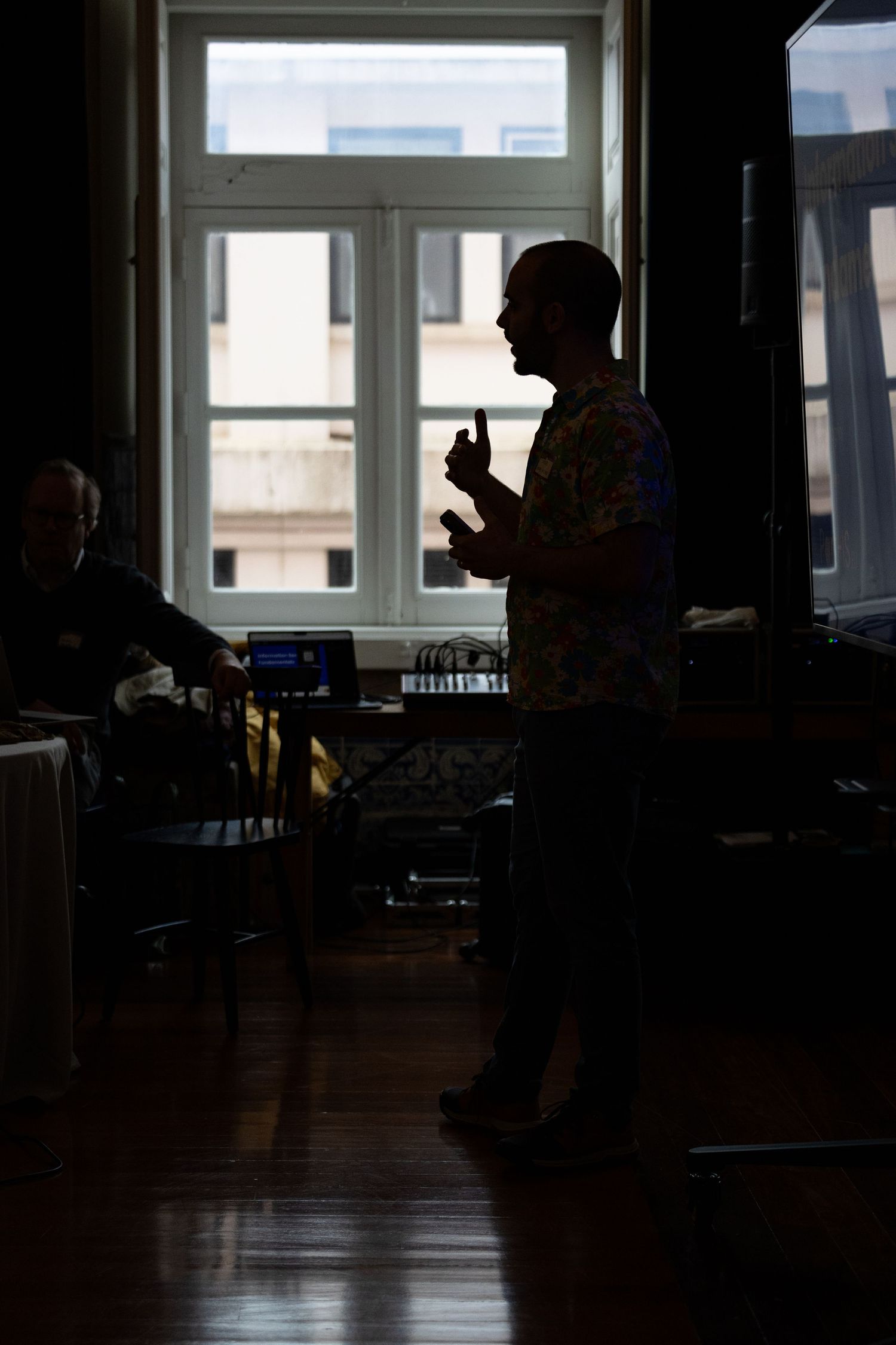 Silhouettes of people in a dimly lit room with large windows.