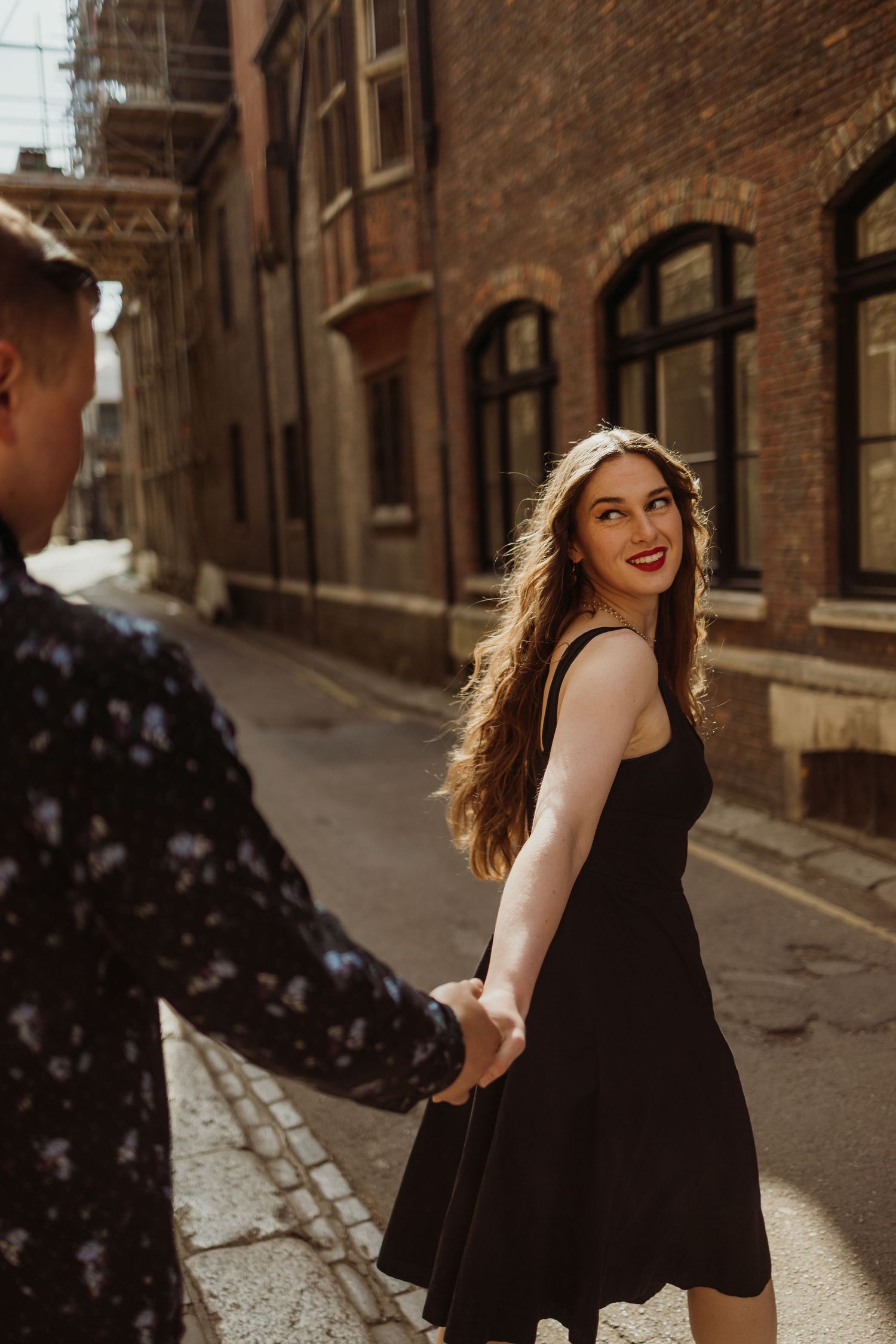 Playful moment captured in vintage brick alleyway with dramatic lighting.