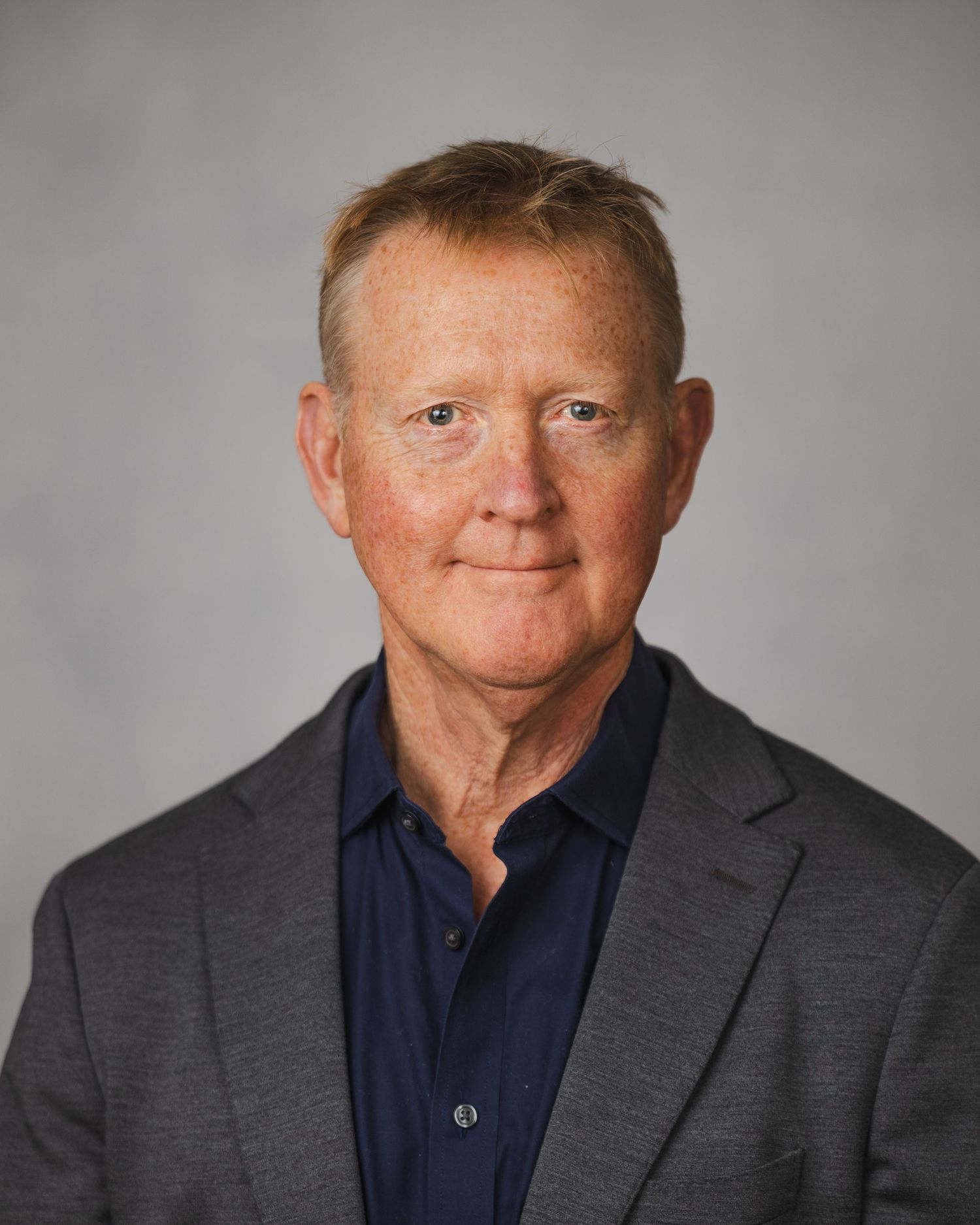 Professional headshots of person in business attire against neutral grey background.