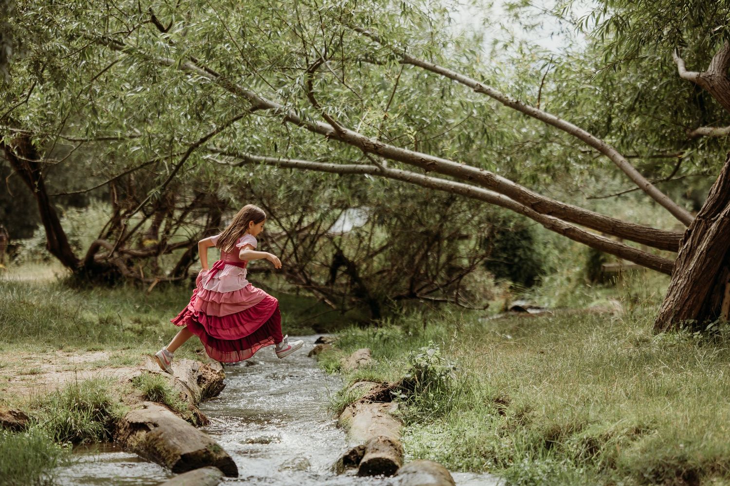 People enjoying a playful moment in a natural wooded setting with fallen trees.