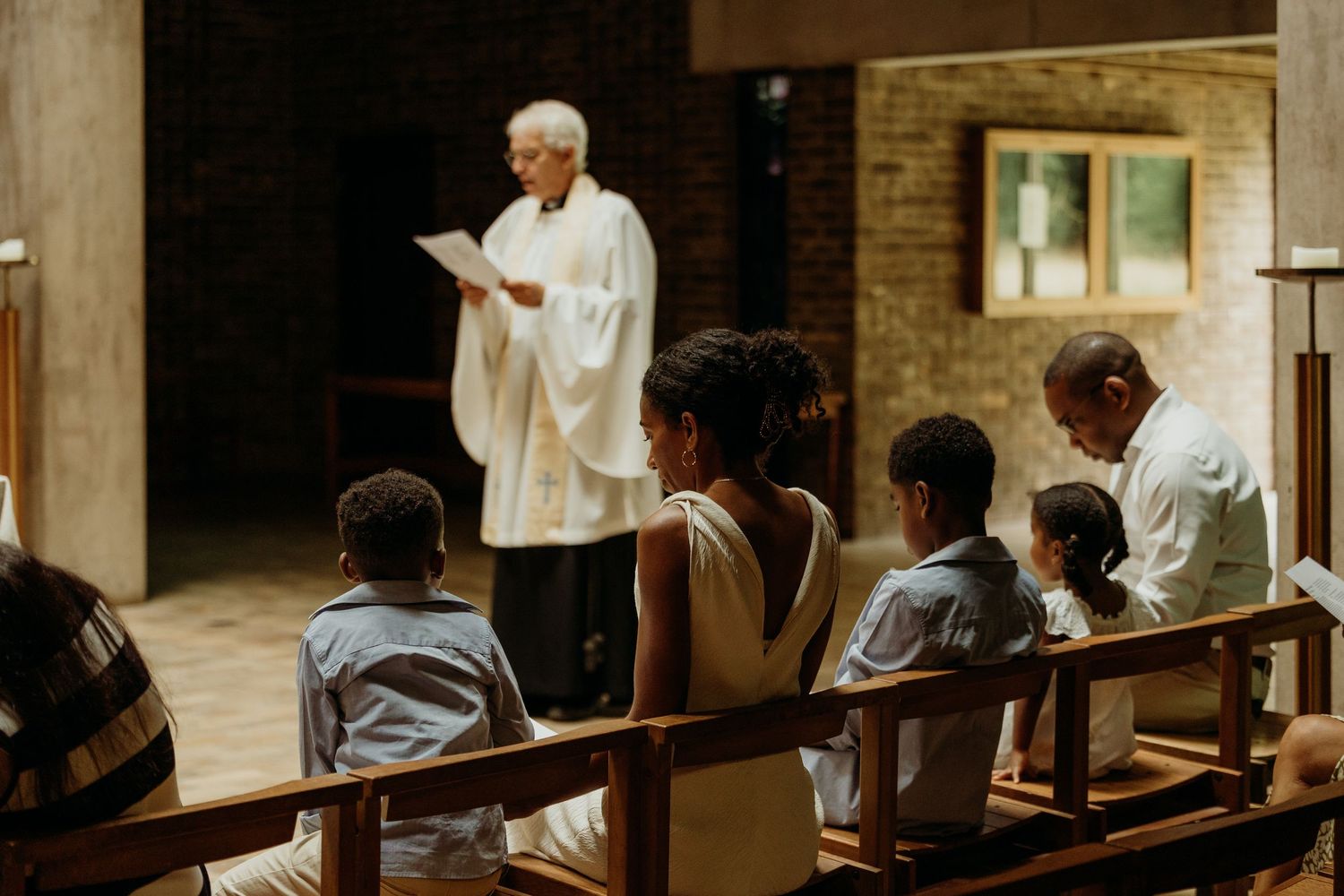 Interior view of a modern church space with people seated along benches.