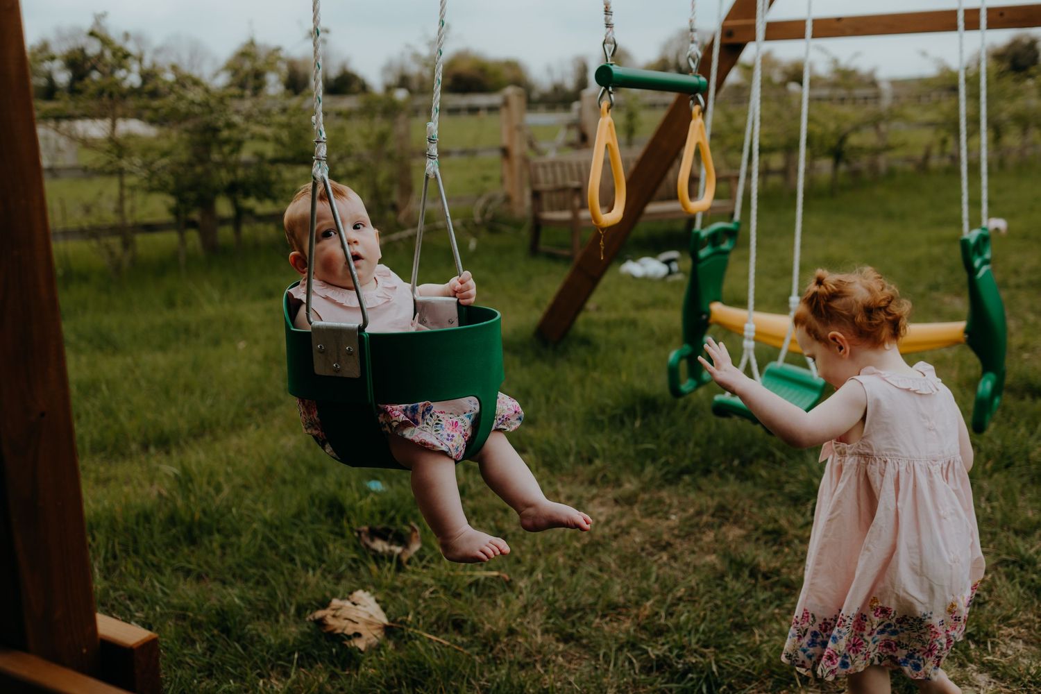 Children playing on outdoor swings in a backyard playground setting.