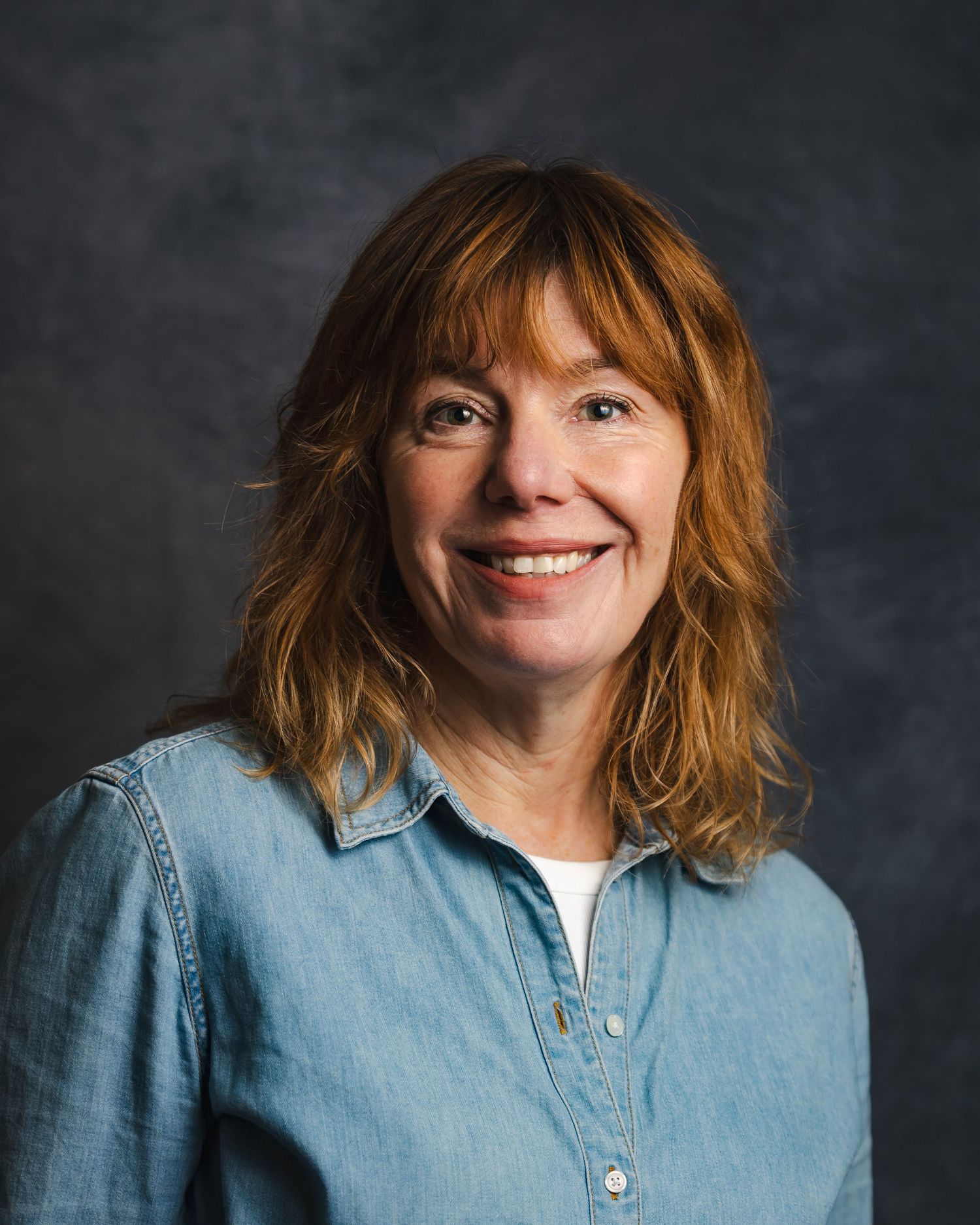 Studio portraits in denim shirt showing various expressions against dark background.