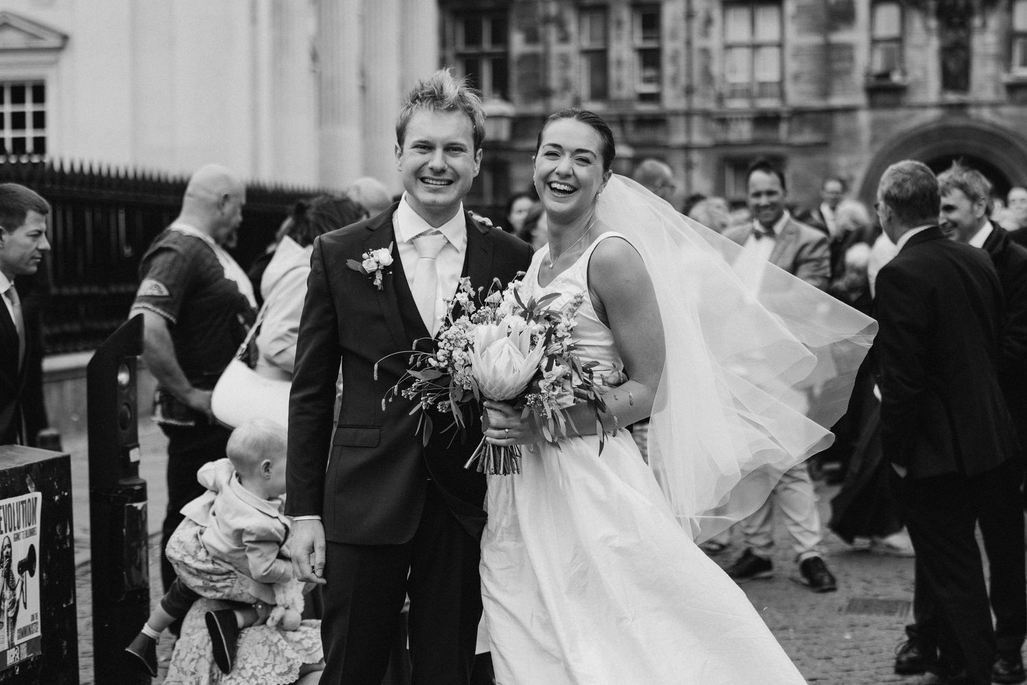 Black and white wedding photos showing joyful moments outside a historic building.