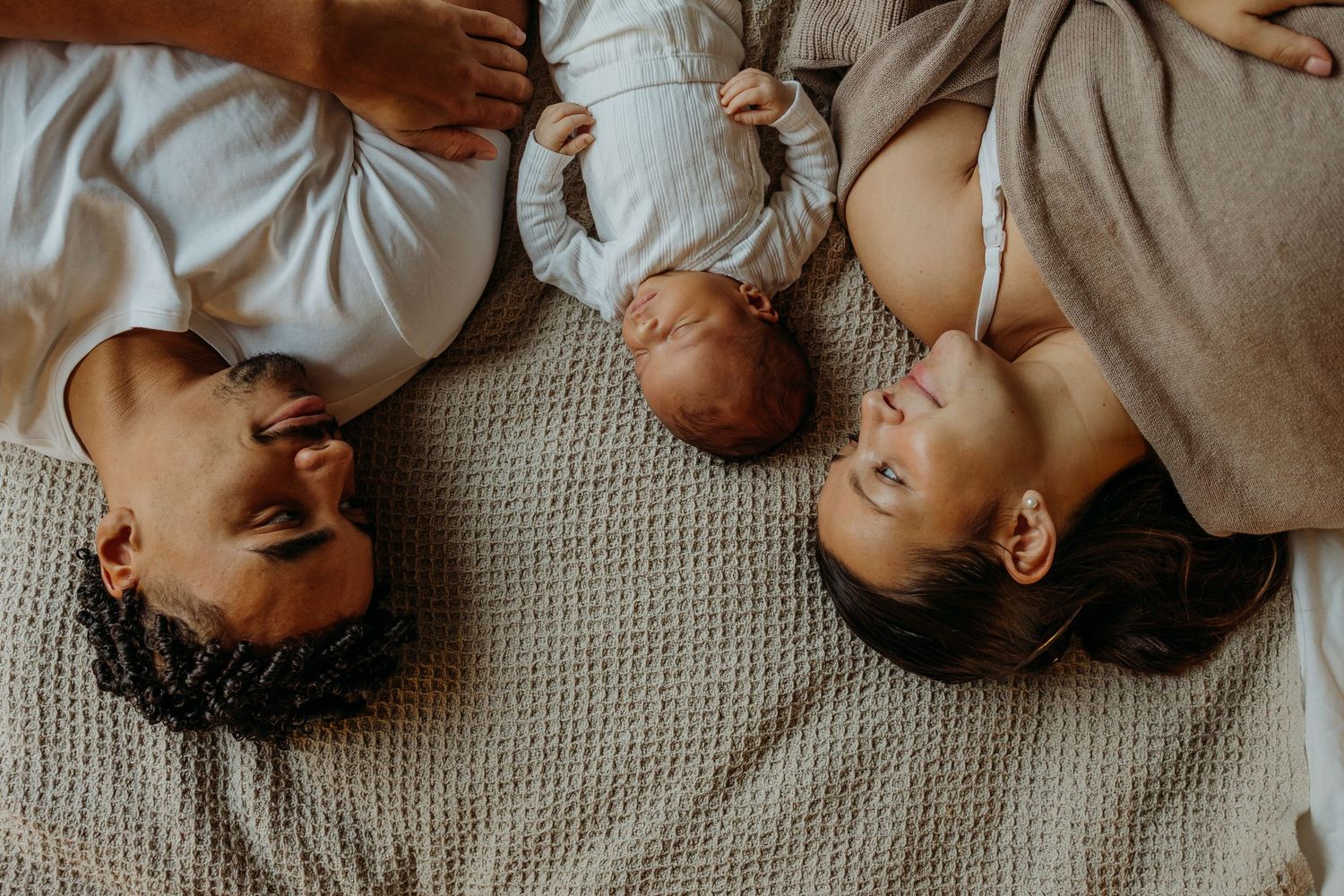Close-up shots of family members lying together on a gray carpet.