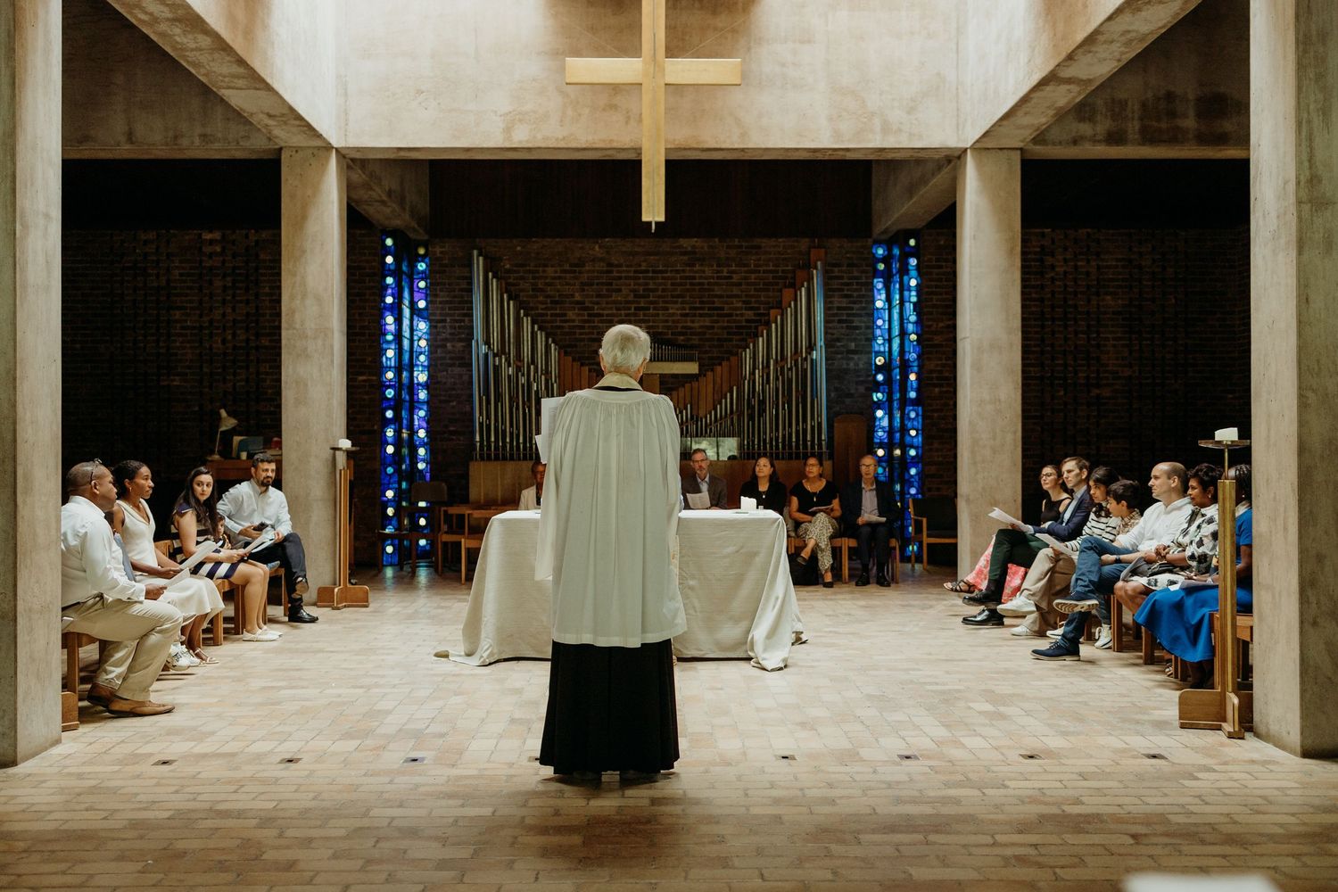 Modern church sanctuary with concrete pillars and stained glass windows.