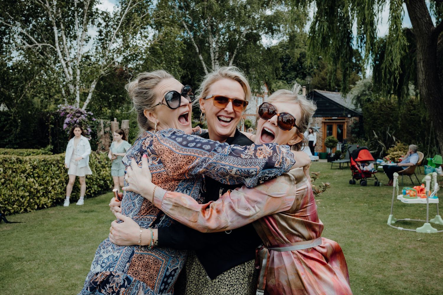 Guests celebrating at an outdoor garden party with hugs and laughter.
