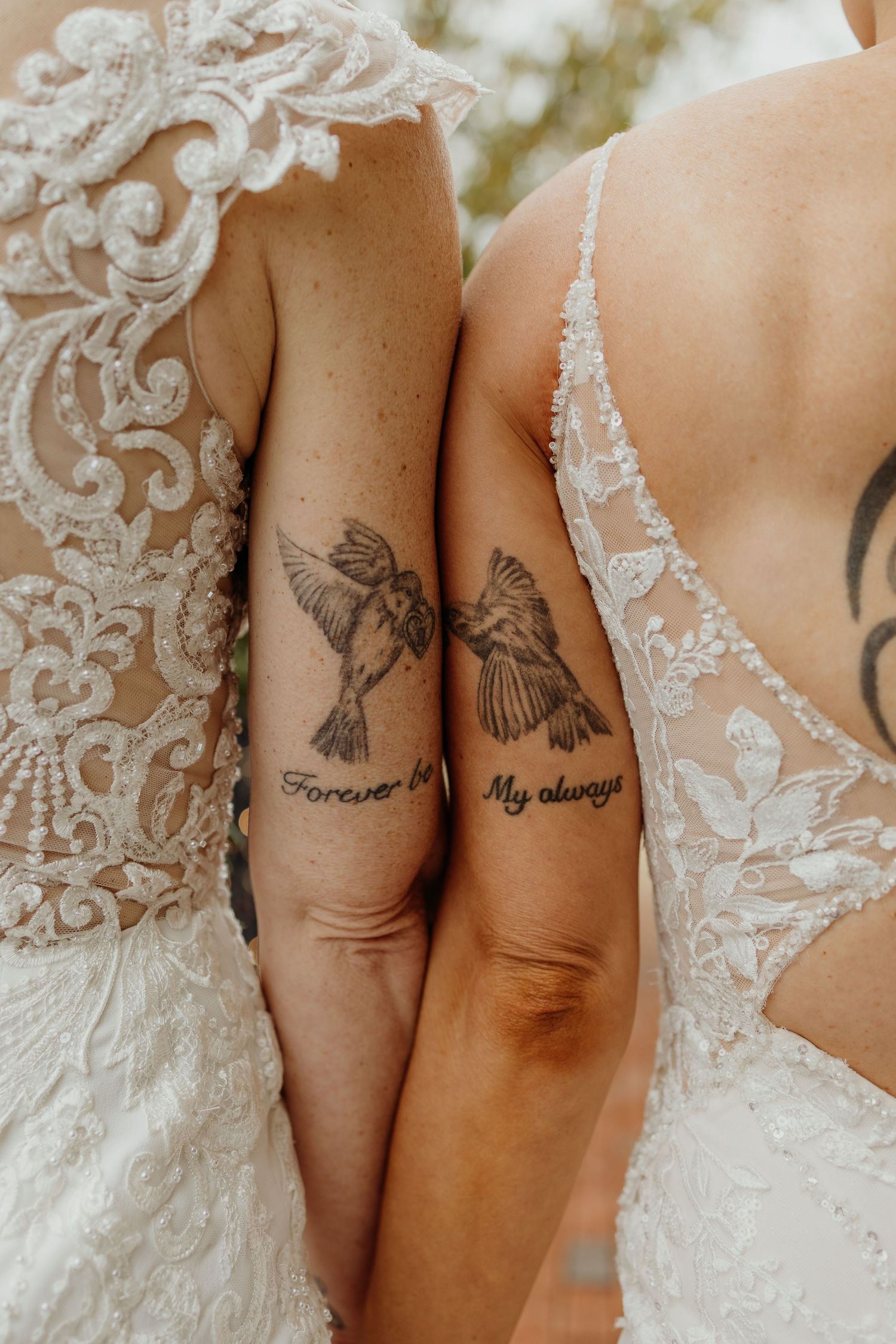 Close-up of matching bird tattoos and lace wedding dress details.