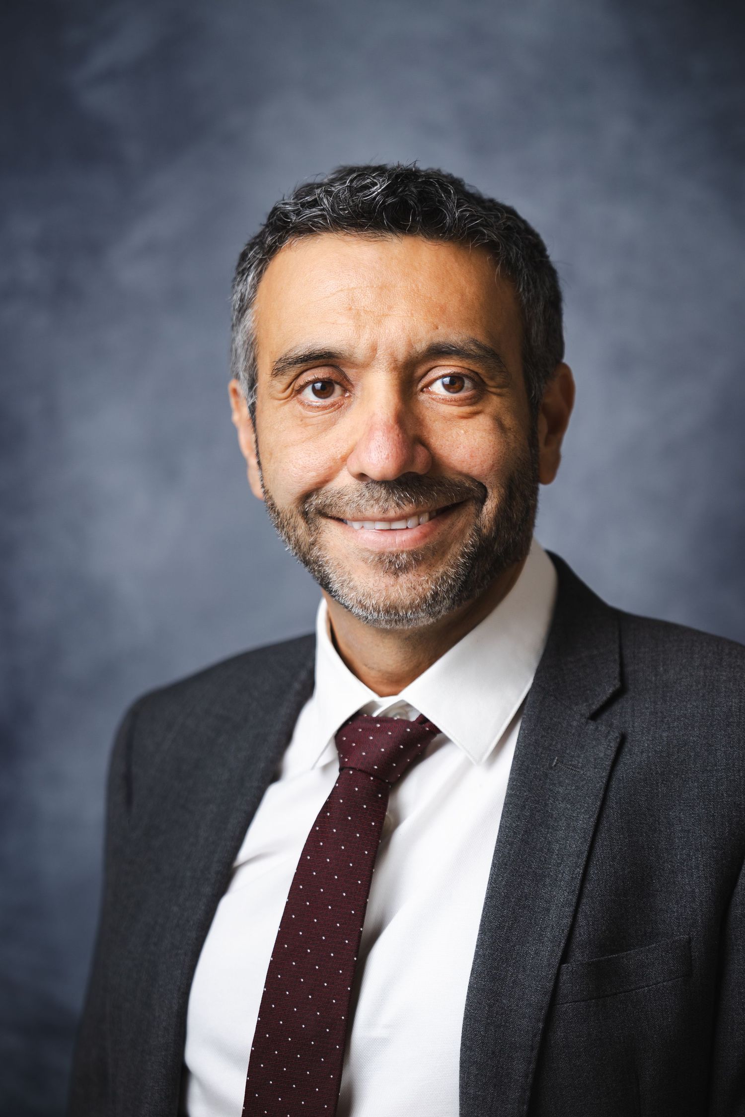 Business portrait series showing different expressions in dark suit and burgundy tie.