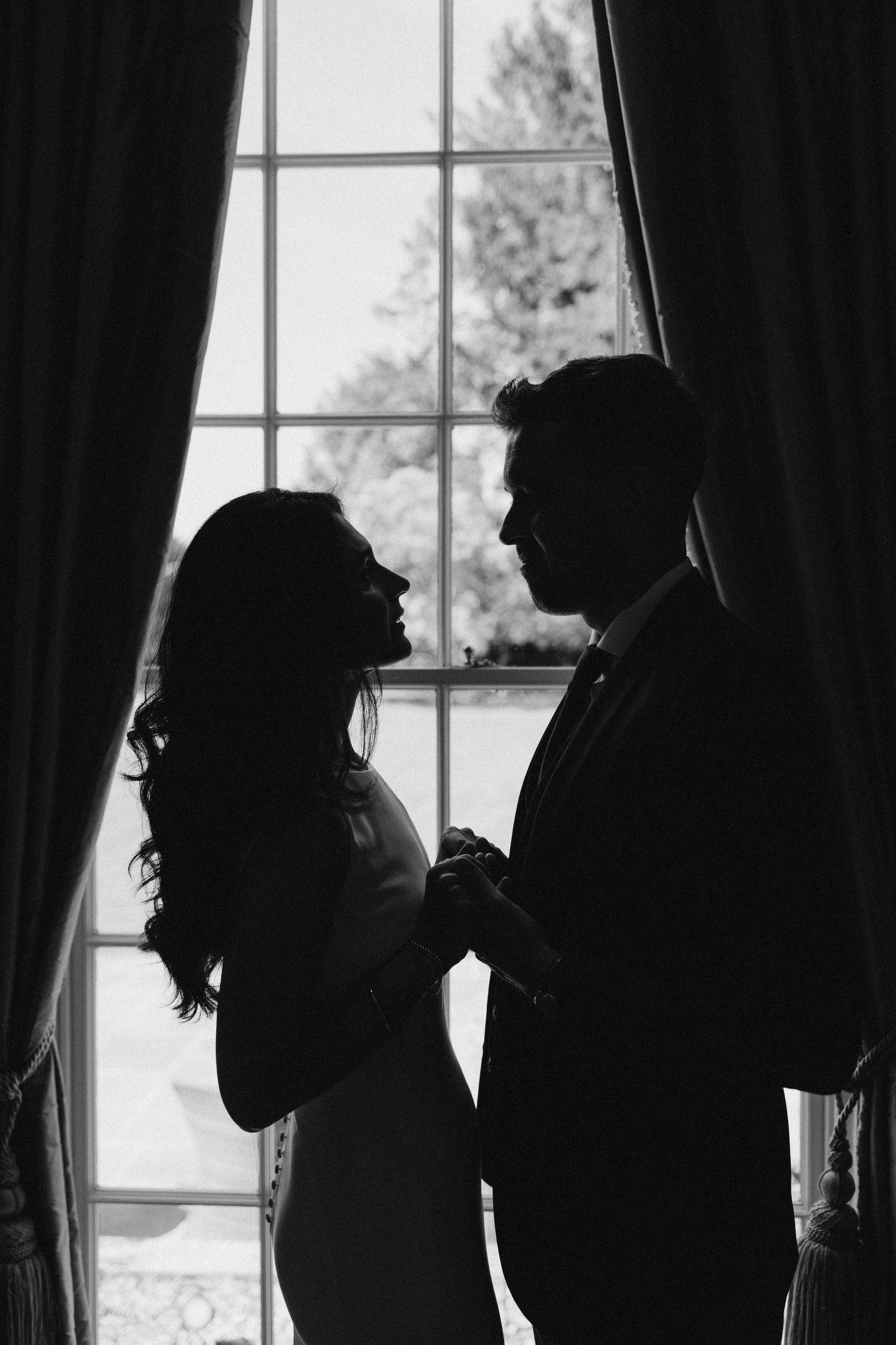 Silhouetted couple against bright windows creating romantic wedding portraits.