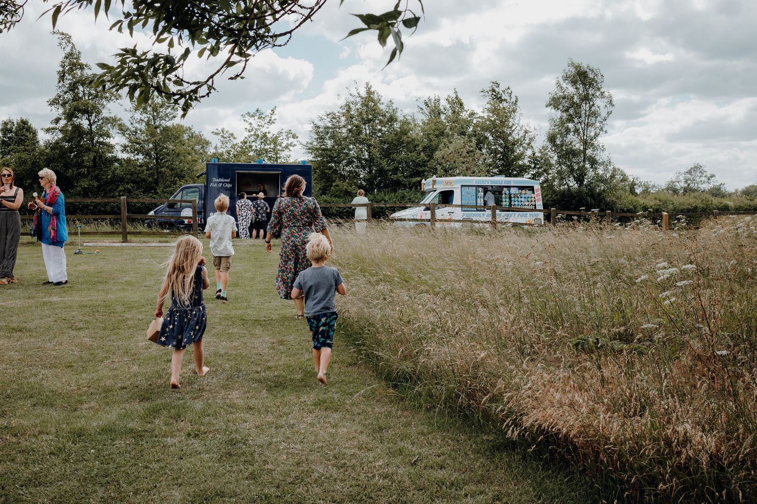 Wide angle view of people enjoying an outdoor summer gathering in a grassy field.