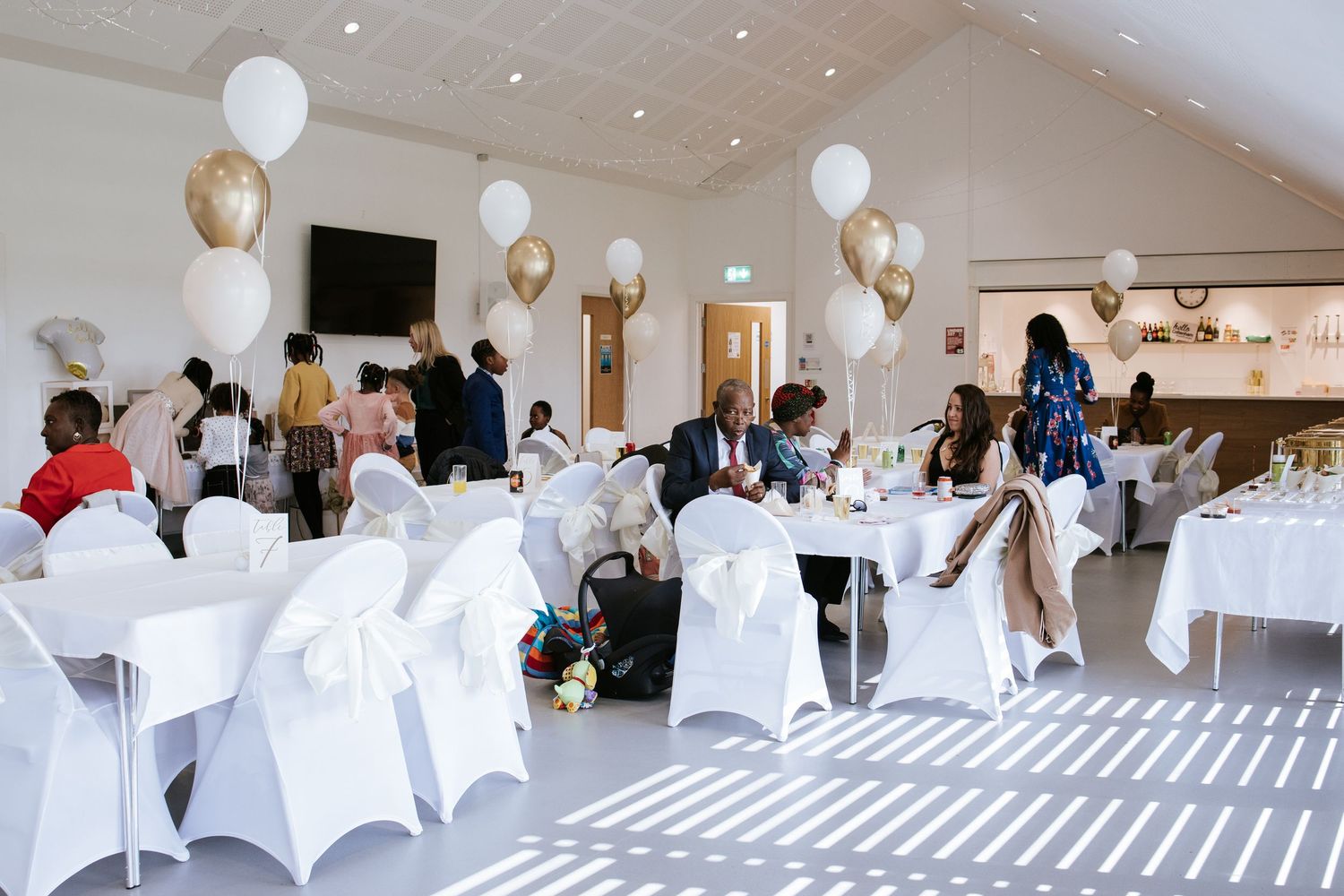 Elegant event space with white chair covers and balloon decorations for a special occasion.