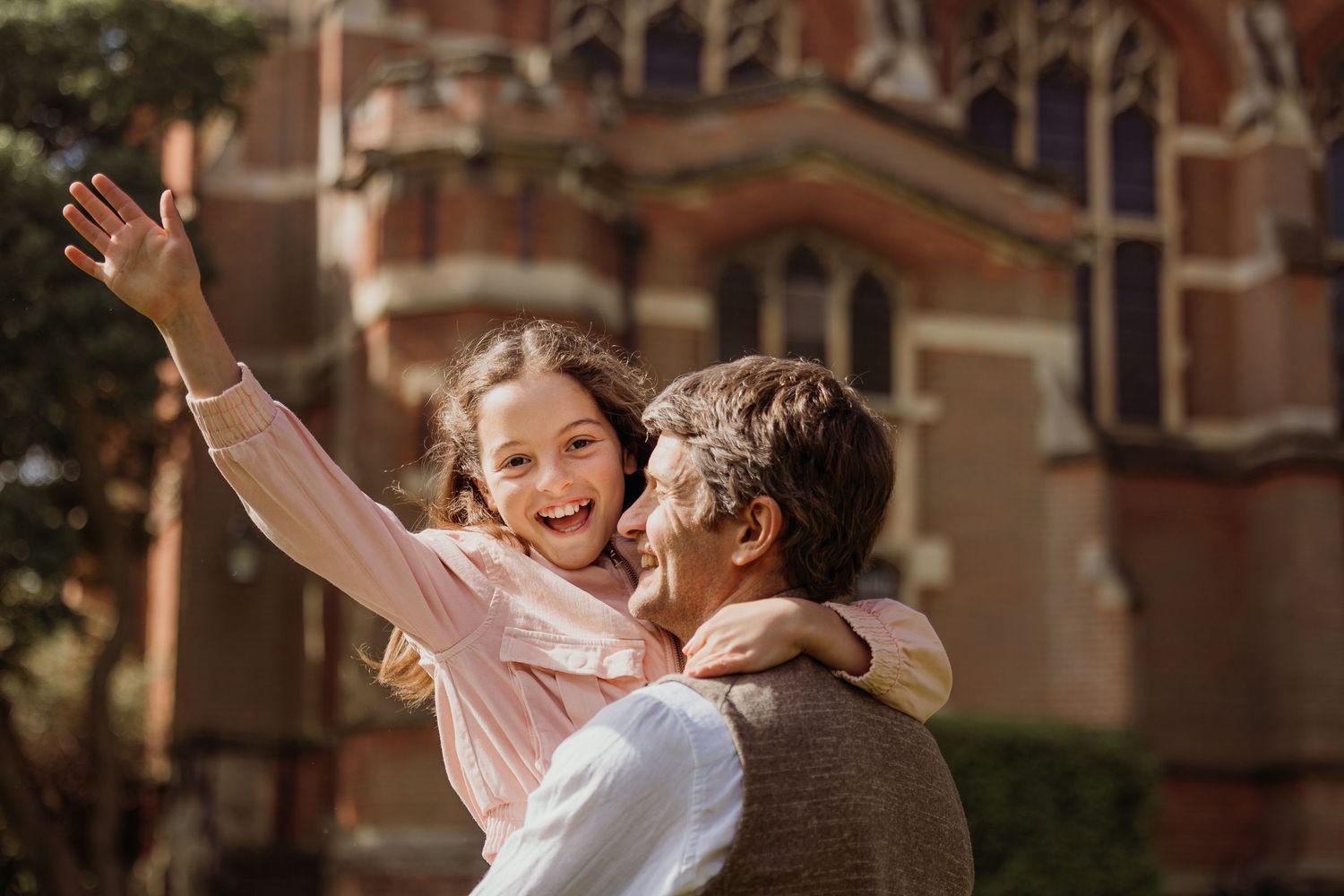 A joyful moment captured in warm sunlight against a historic brick building backdrop.