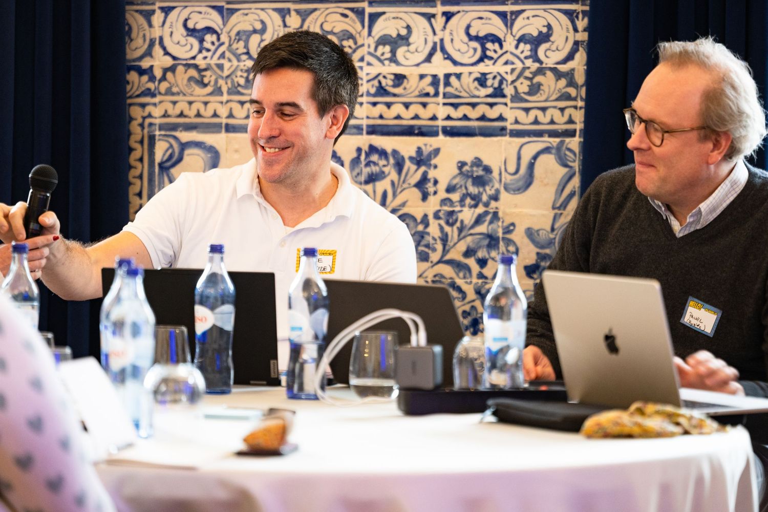Business meeting in an elegant room with ornate blue and white tiled walls.