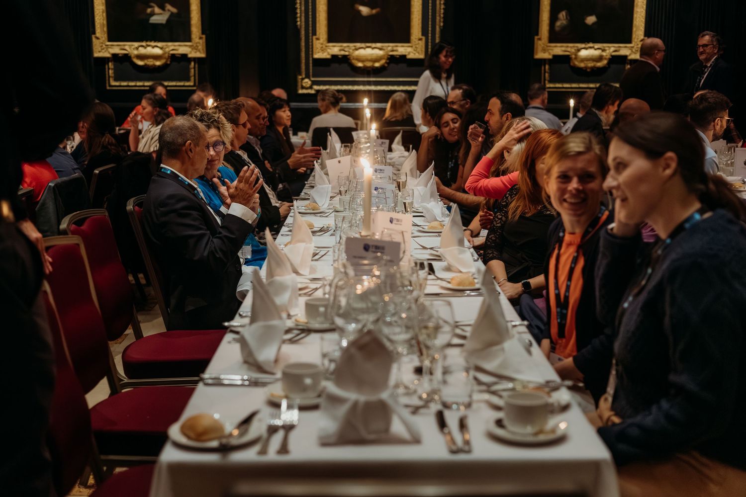 Elegant dinner setting with long tables and white tablecloths in a formal dining room.