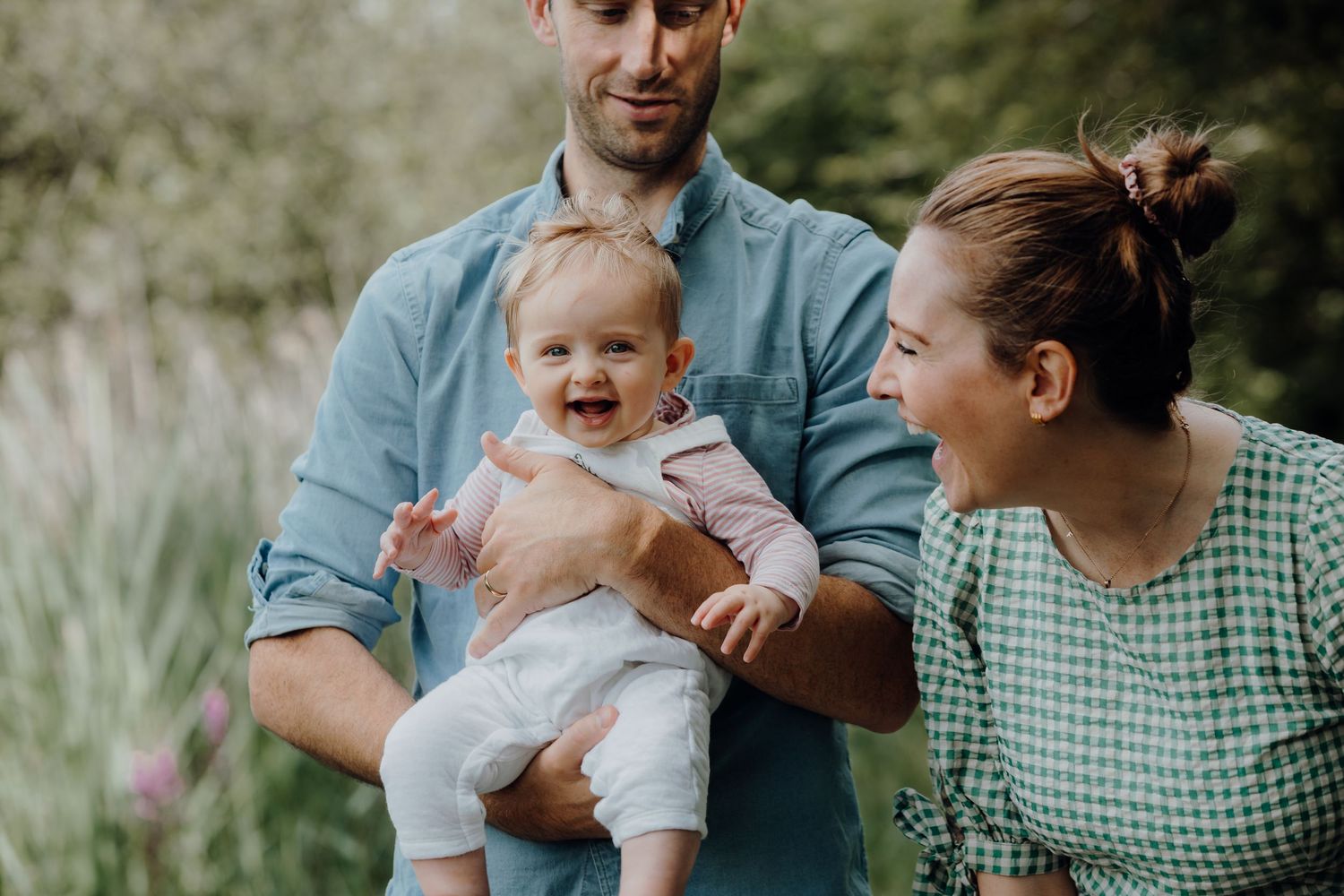 Family enjoying a tender moment together outdoors in a natural setting with greenery in the background.