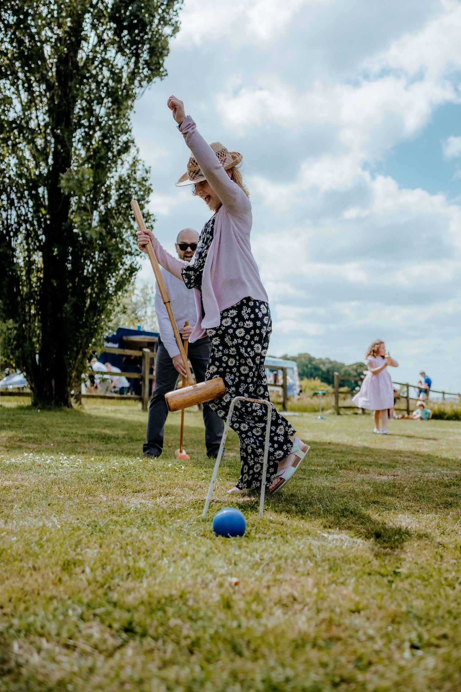 People playing outdoor games on a grassy field under cloudy skies.