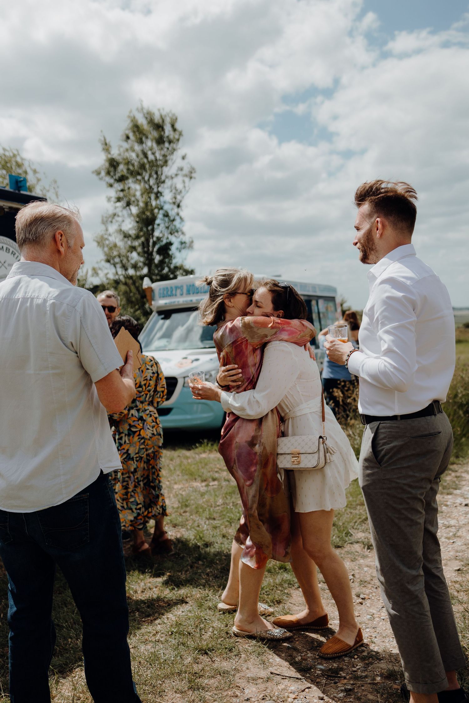 Guests sharing warm embraces during an outdoor celebration.