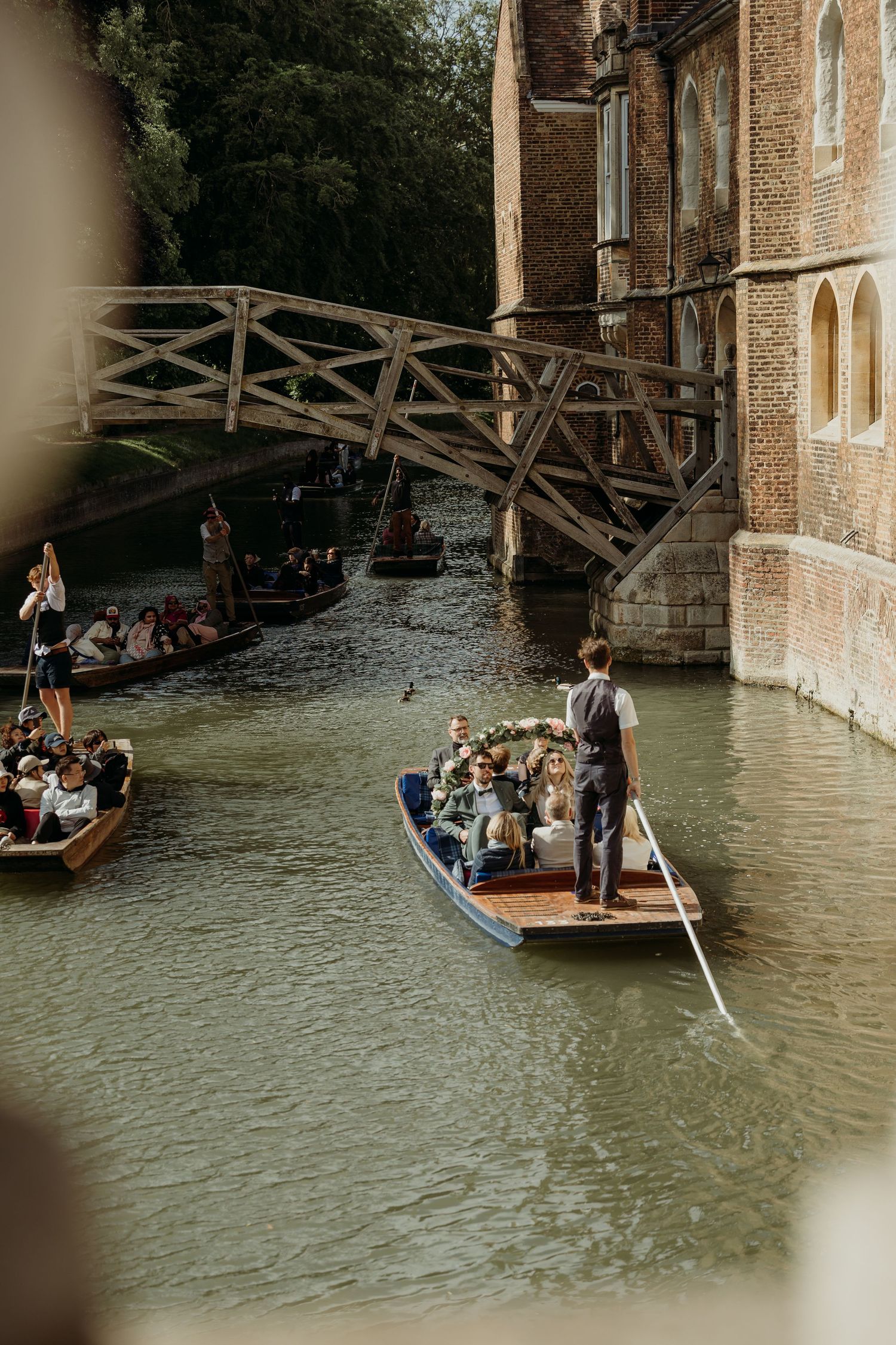 Punting boats glide under historic stone bridges on a scenic river.