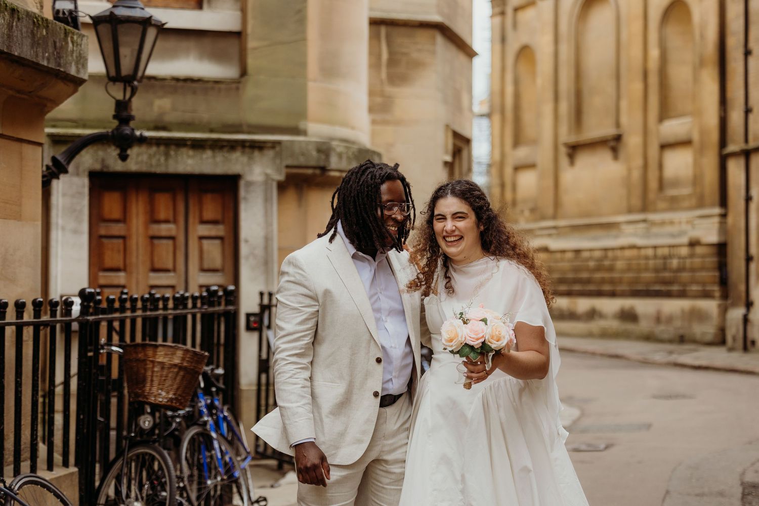 Couple walks hand-in-hand along historic stone building with ornate architecture.