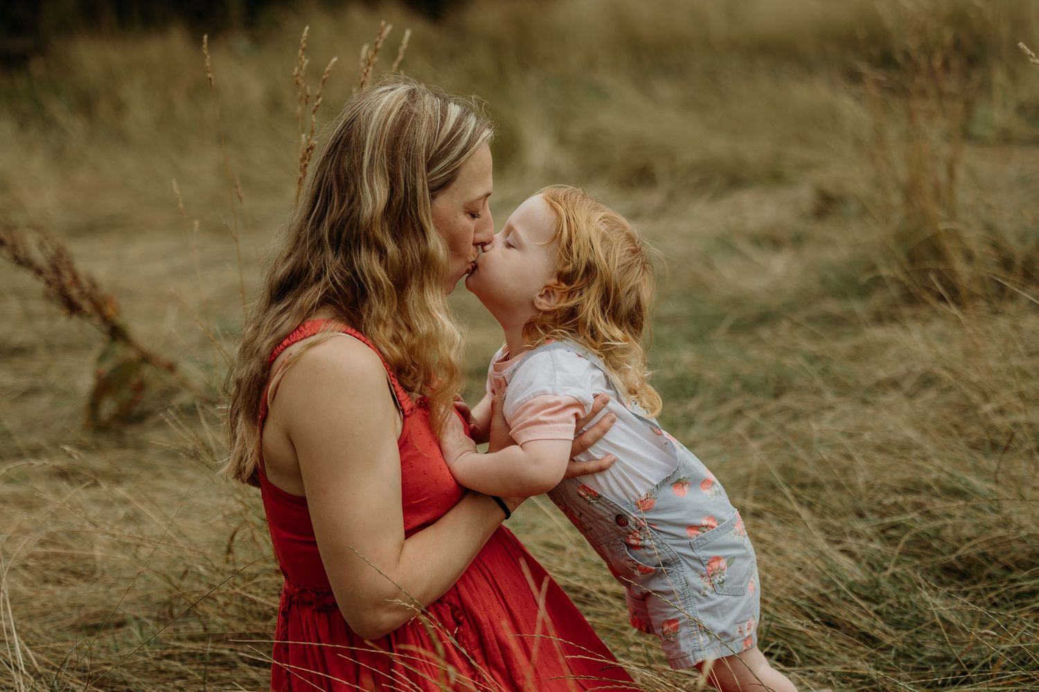 A tender moment captured in a grassy field during golden hour.