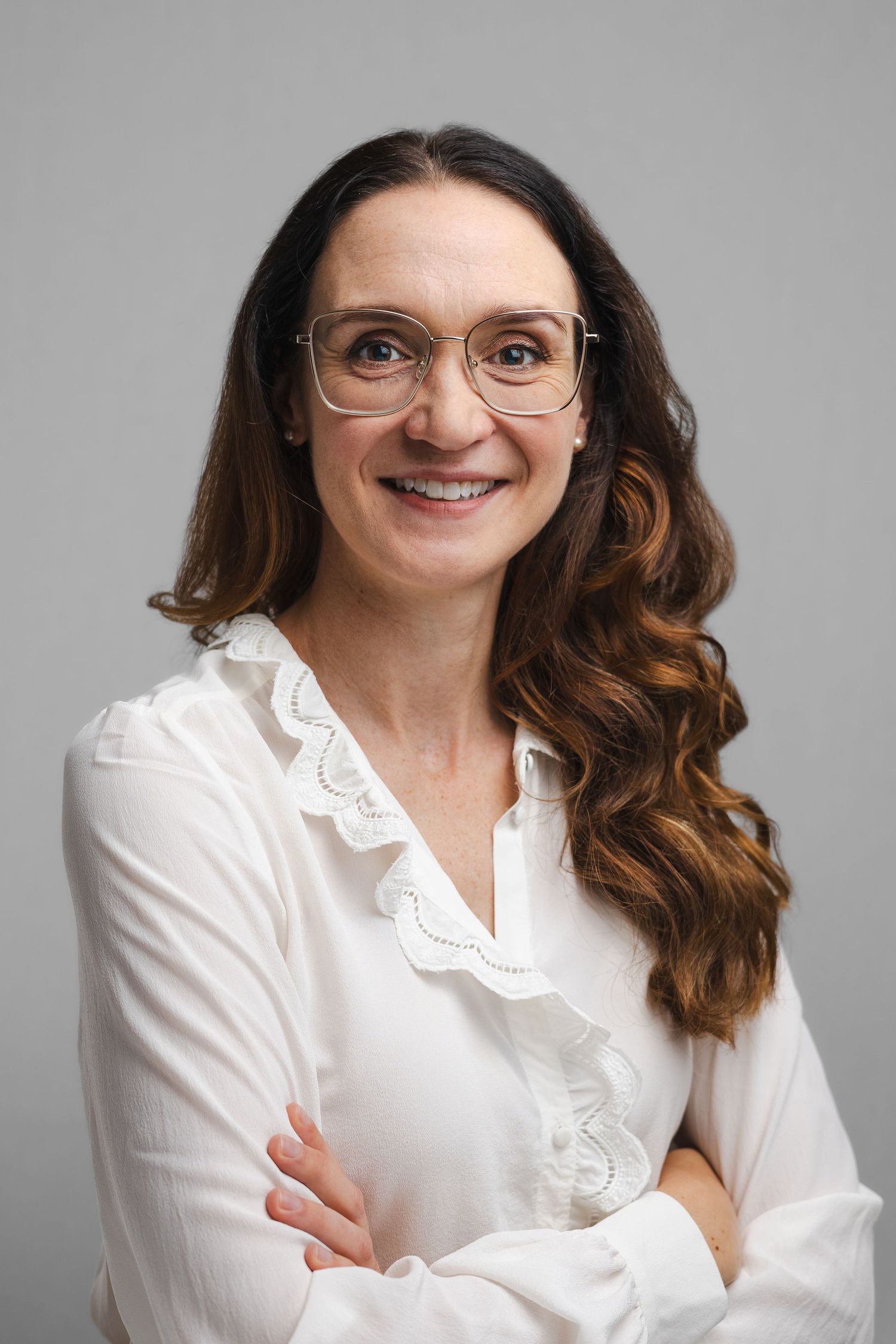 Professional headshots of someone wearing a white ruffled blouse against a light gray backdrop.