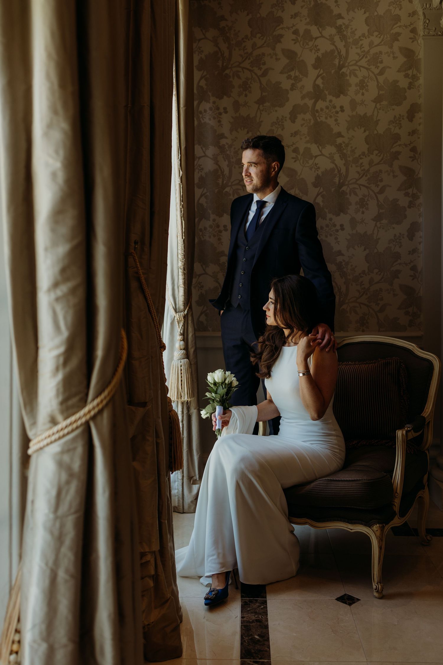 Wedding portraits in a luxurious room with damask wallpaper and vintage furniture.