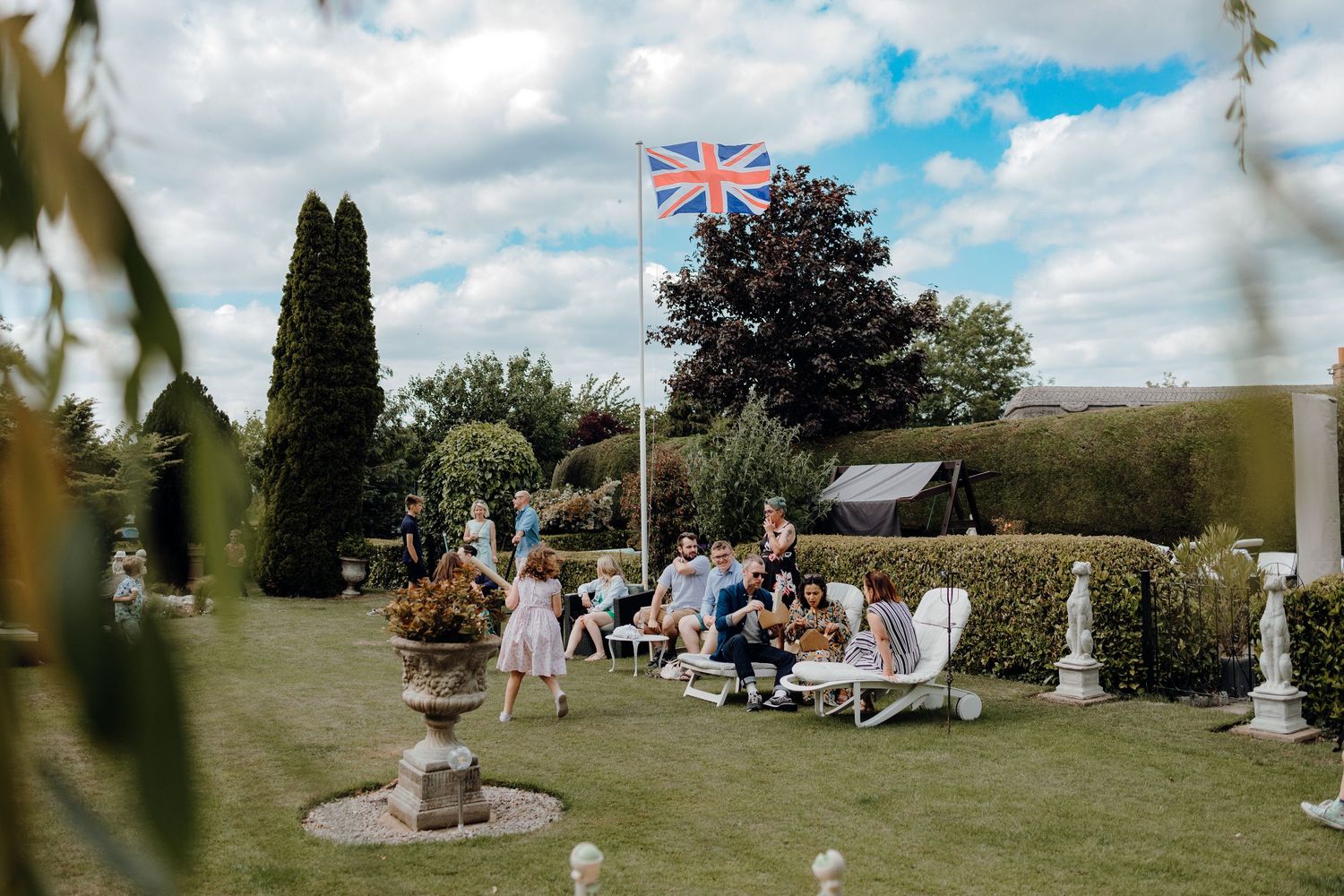 Panoramic view of a garden event space with British flag flying under partly cloudy skies.