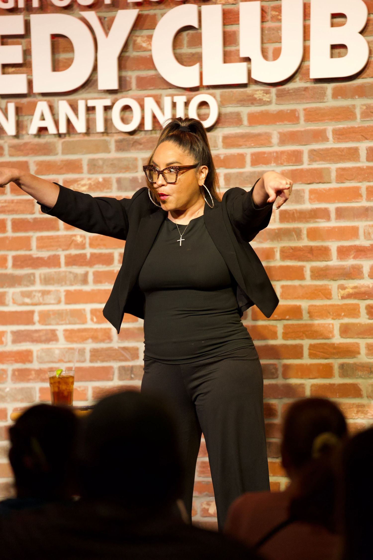 Comedy club performance on brick wall stage with dramatic lighting.