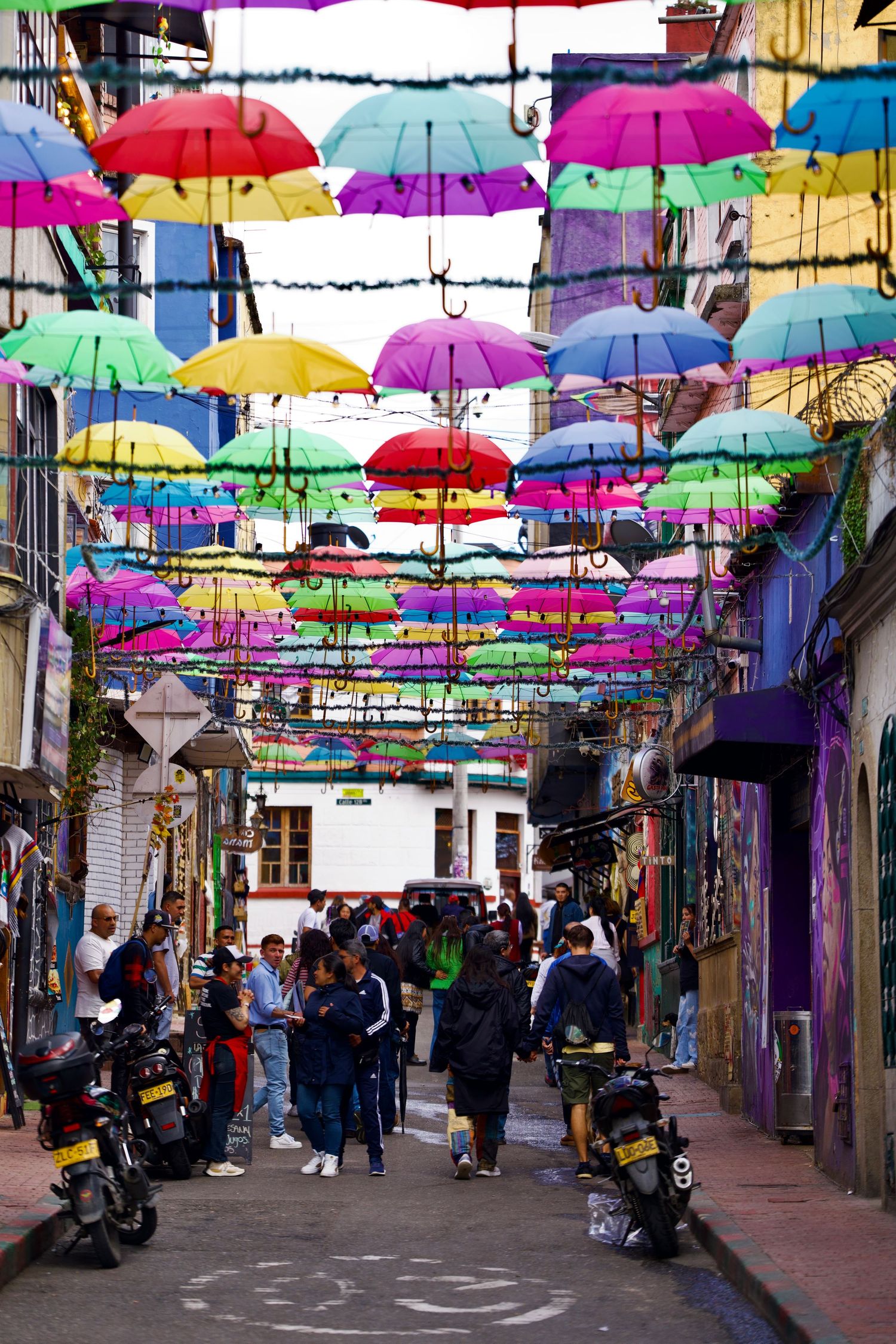 Vibrant multicolored umbrellas hanging over a busy street creating a colorful canopy.