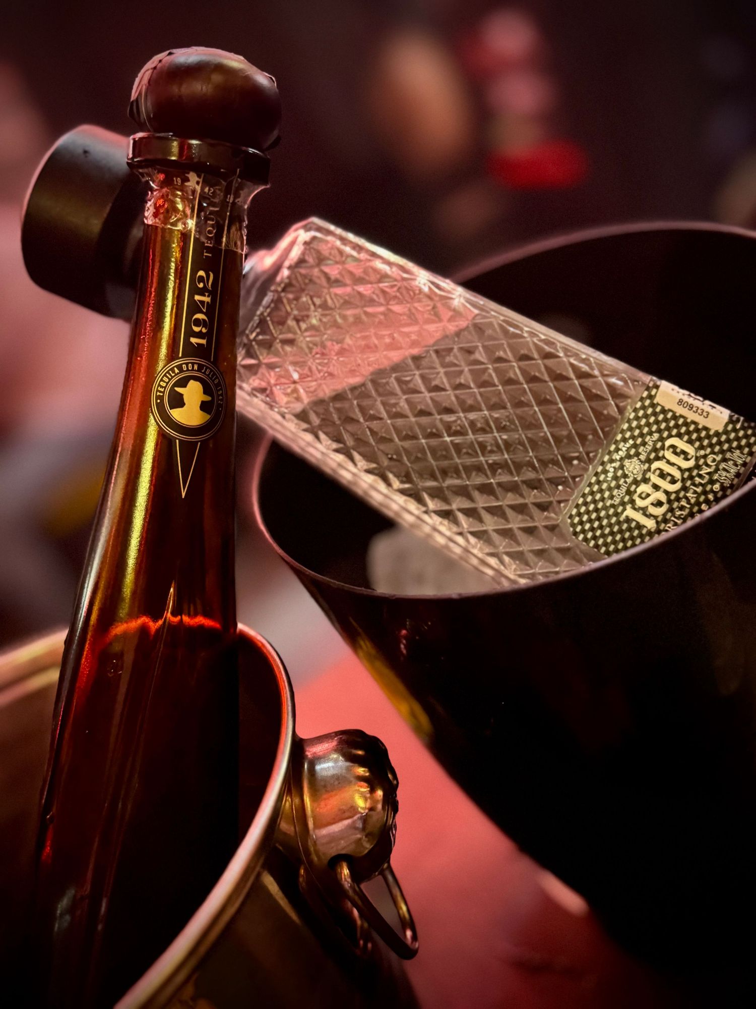 Close-up of beer bottles with textured glass in dim atmospheric lighting.