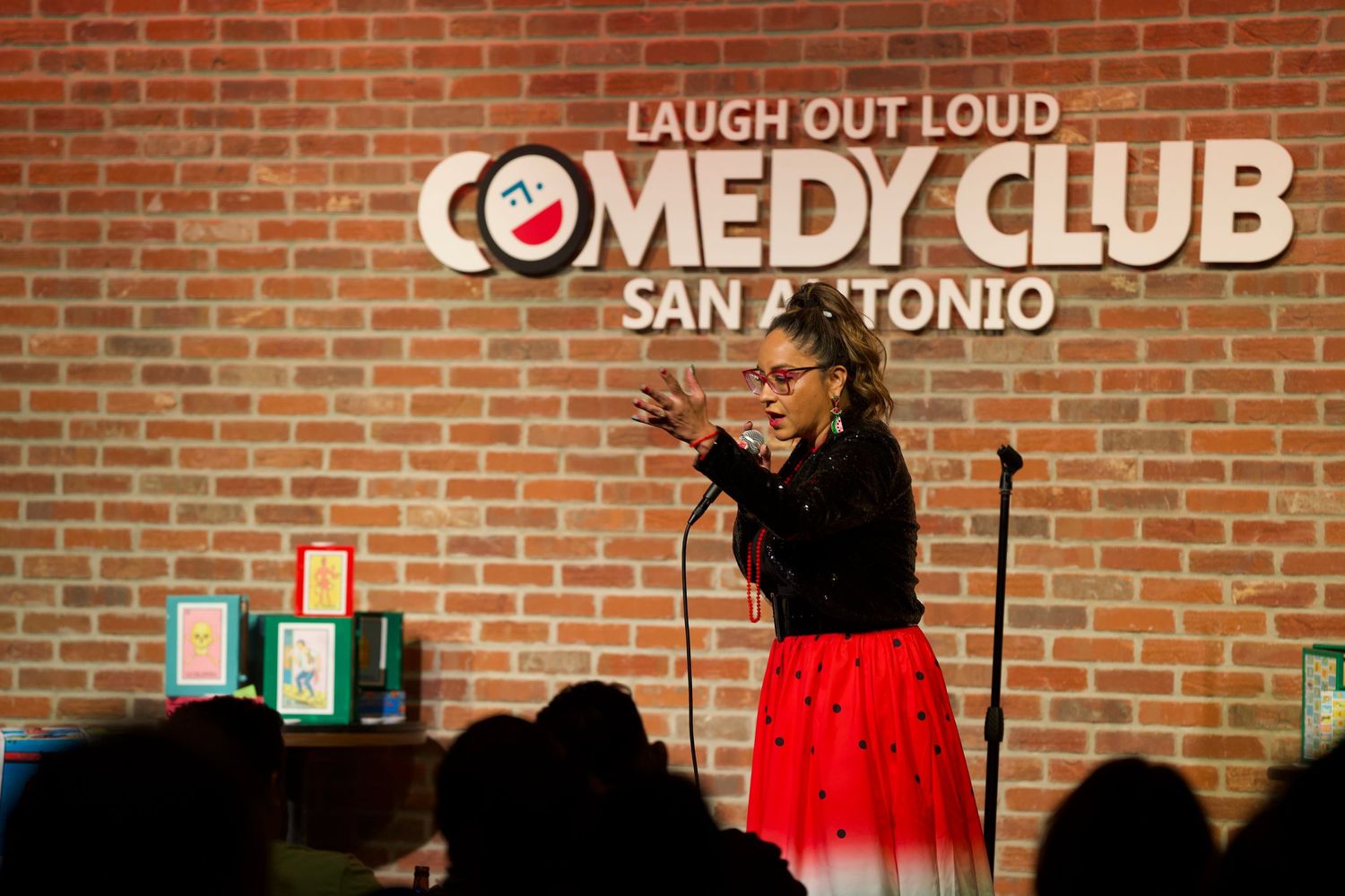 Comedy show performance at Laugh Out Loud Comedy Club with red brick wall background.