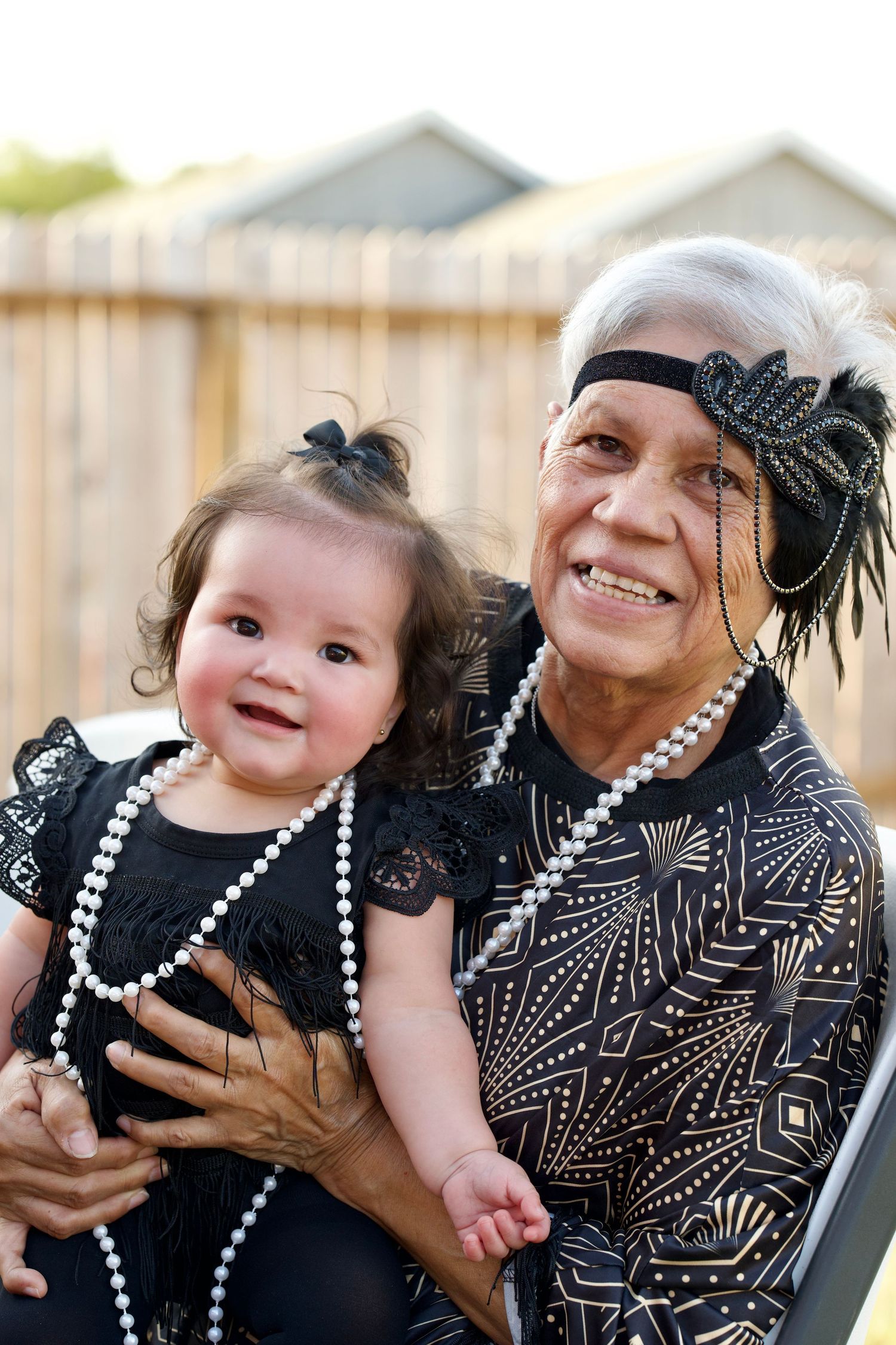 Family wearing black and white outfits and pearl necklaces share joyful moments together.