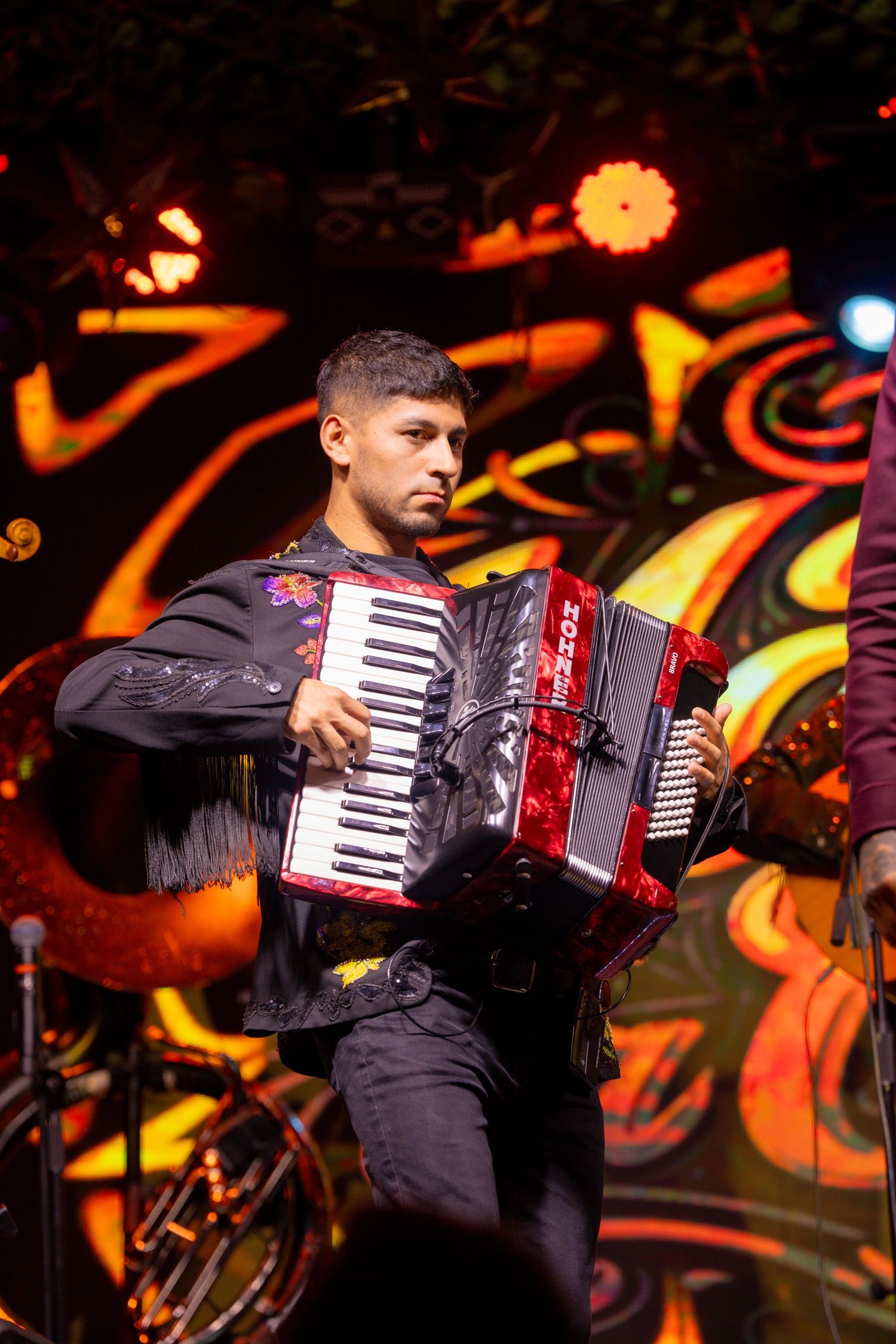 Accordion player performs on stage with vibrant orange lighting effects.